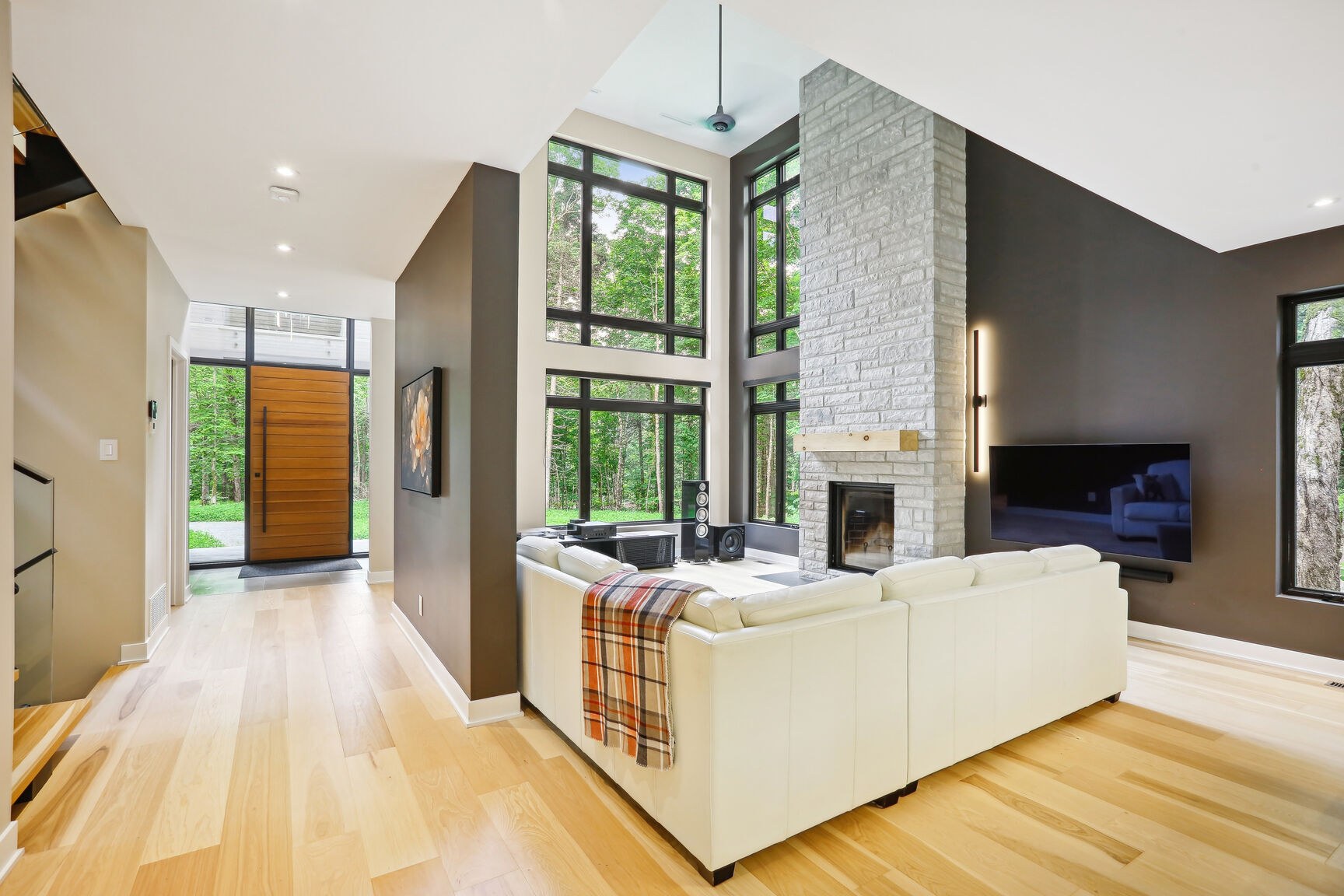 Salon double hauteur vu depuis le couloir, vue sur le boisé.