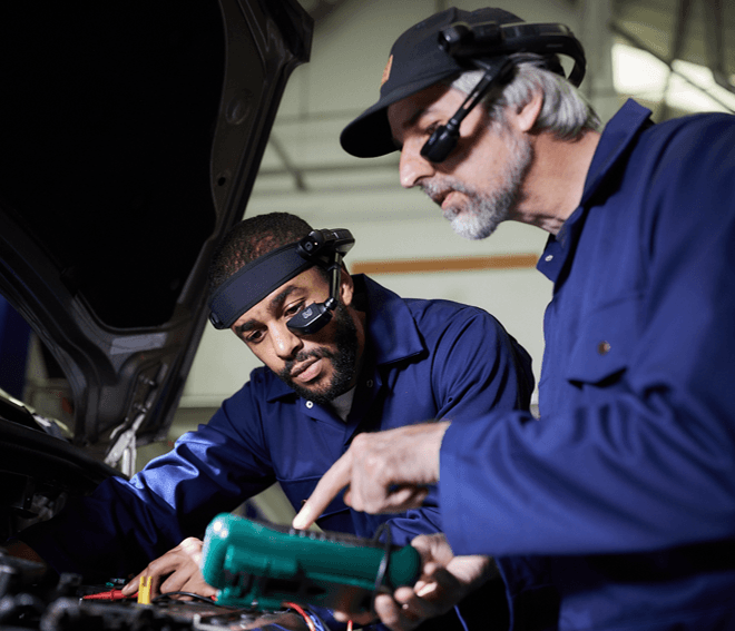 A photo of two automotive engineers working on a car