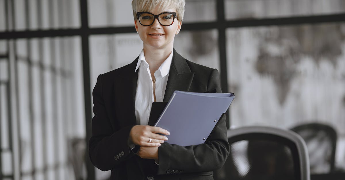 Professional woman in a suit holding a folder in a modern office setting.