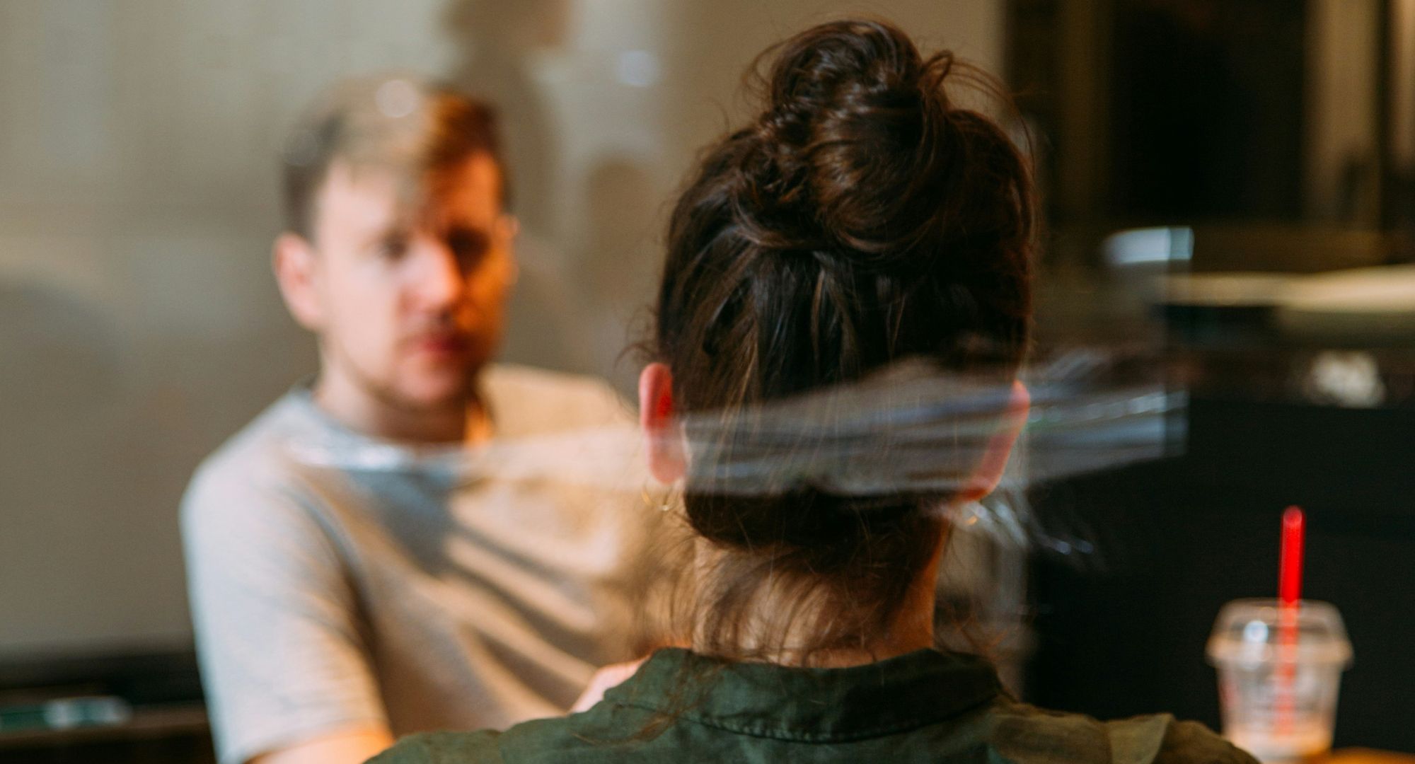 mulher de costas com homem desfocado ao fundo numa sala de reuniões