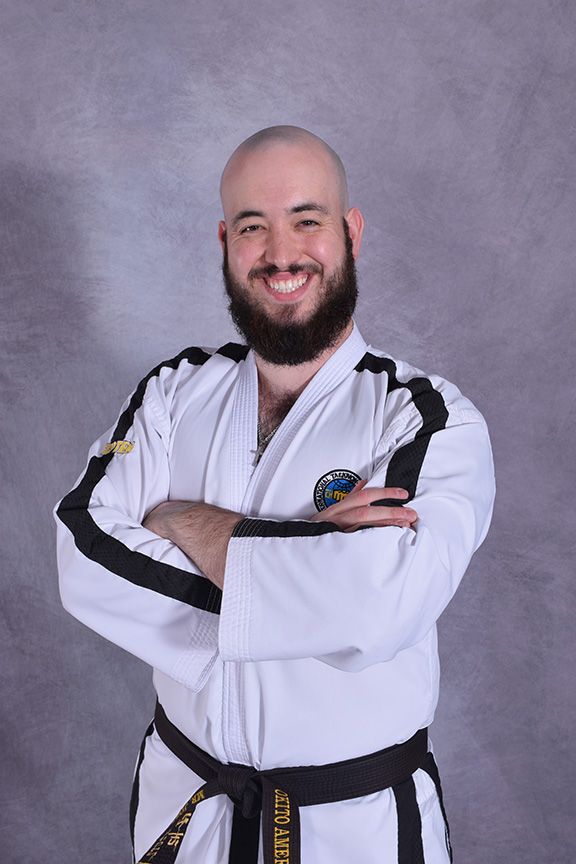 Instructor Joseph posing arms crossed with his martial arts uniform