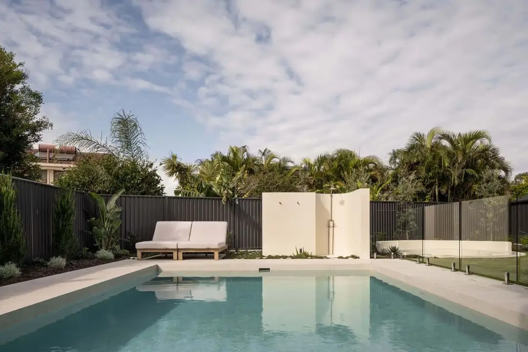 A swimming pool with a glass fence and outdoor shower