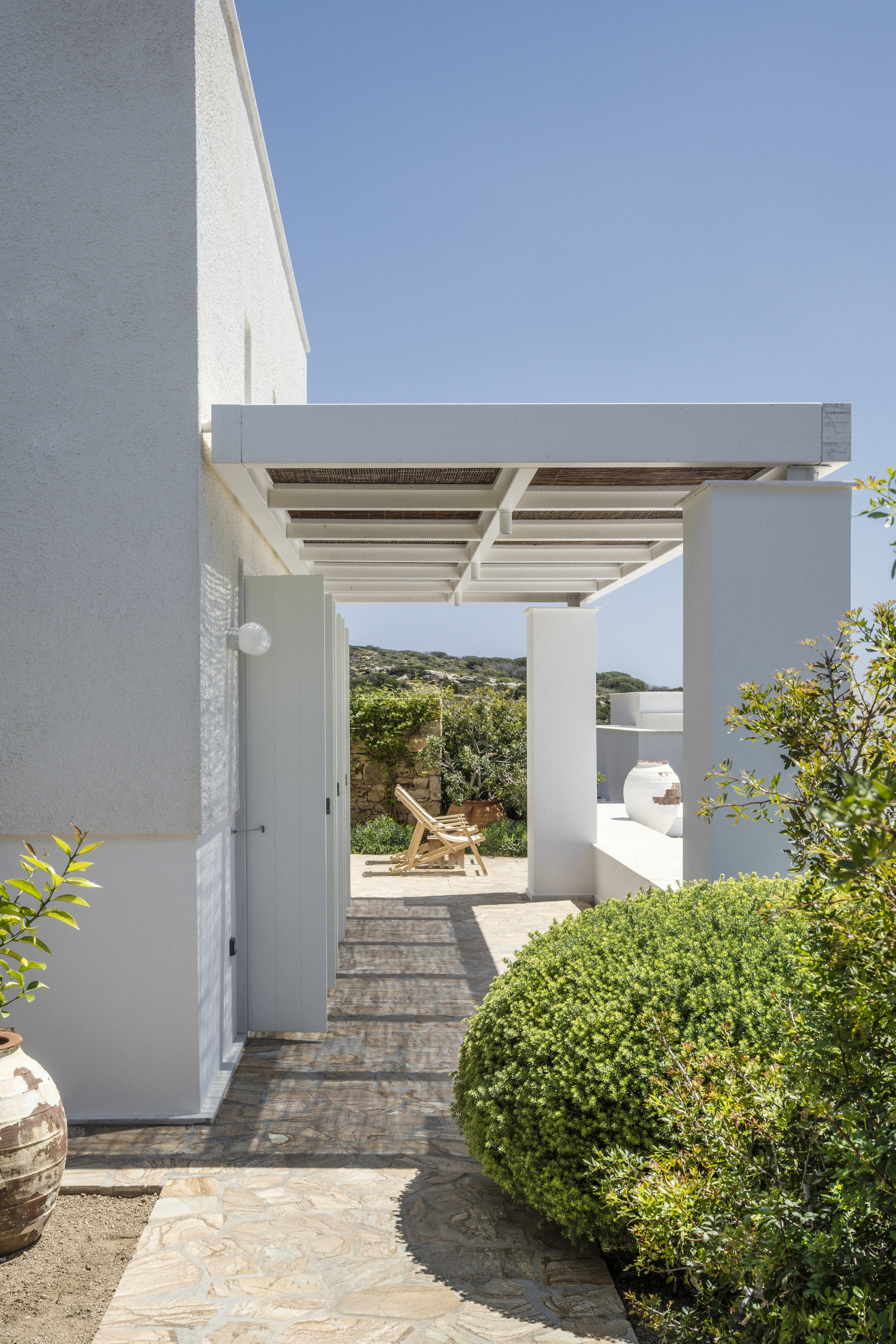 White house with blue skies and lush gardens in Koufonisia Greece