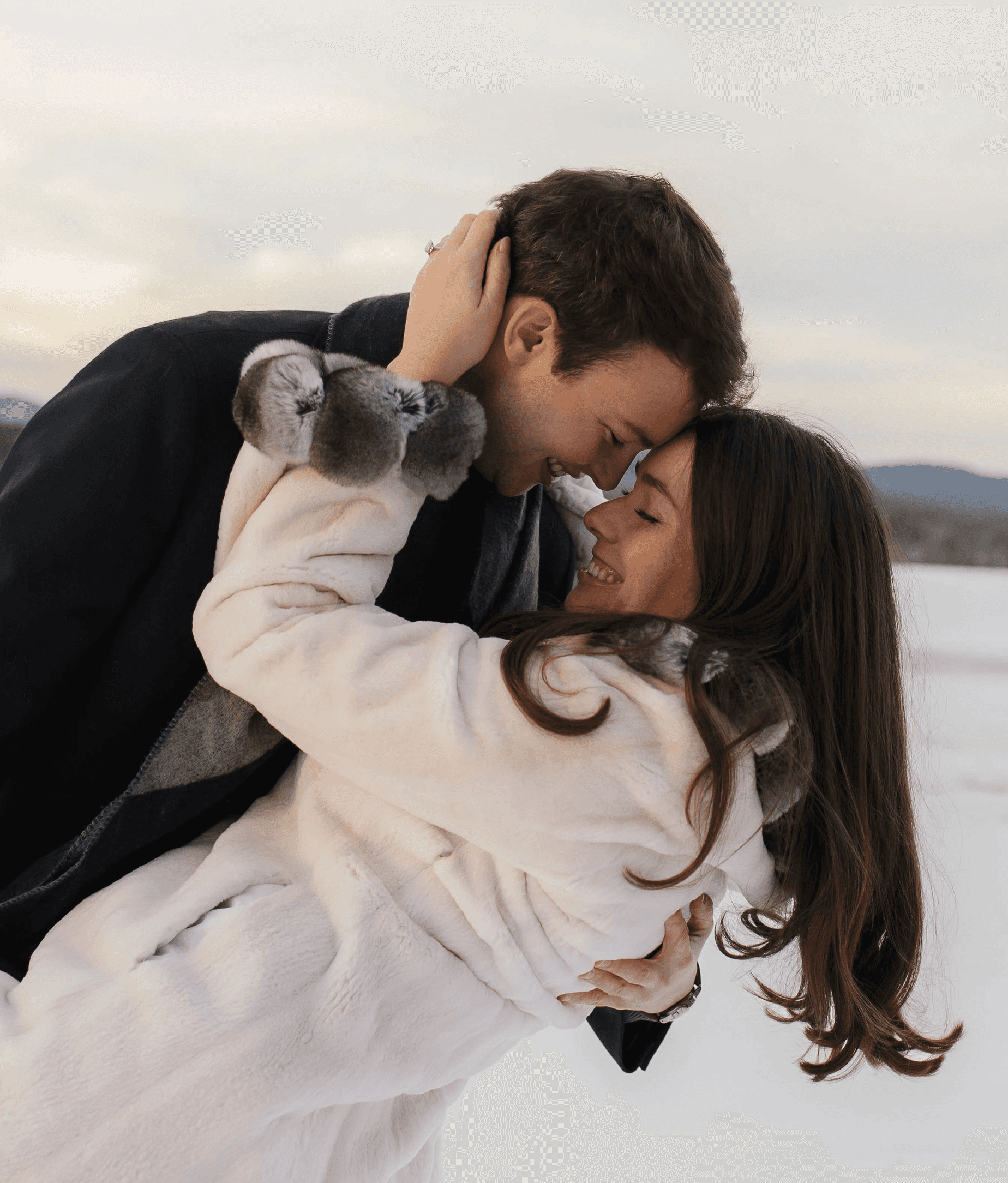 A couple embraces lovingly on a wooden dock.