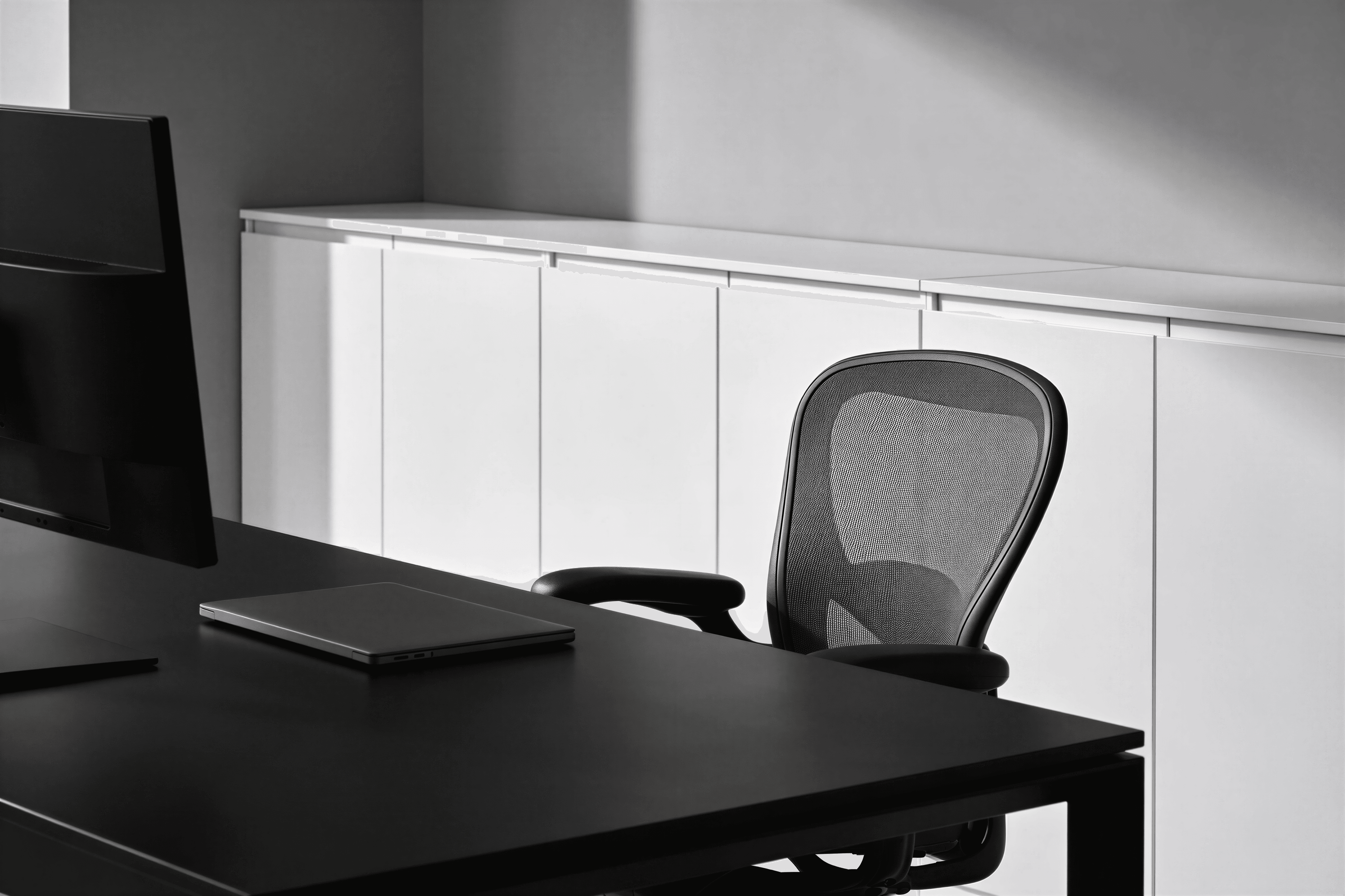 Birou modern negru cu unități albe în fundal, scaun ergonomic și look corporate.