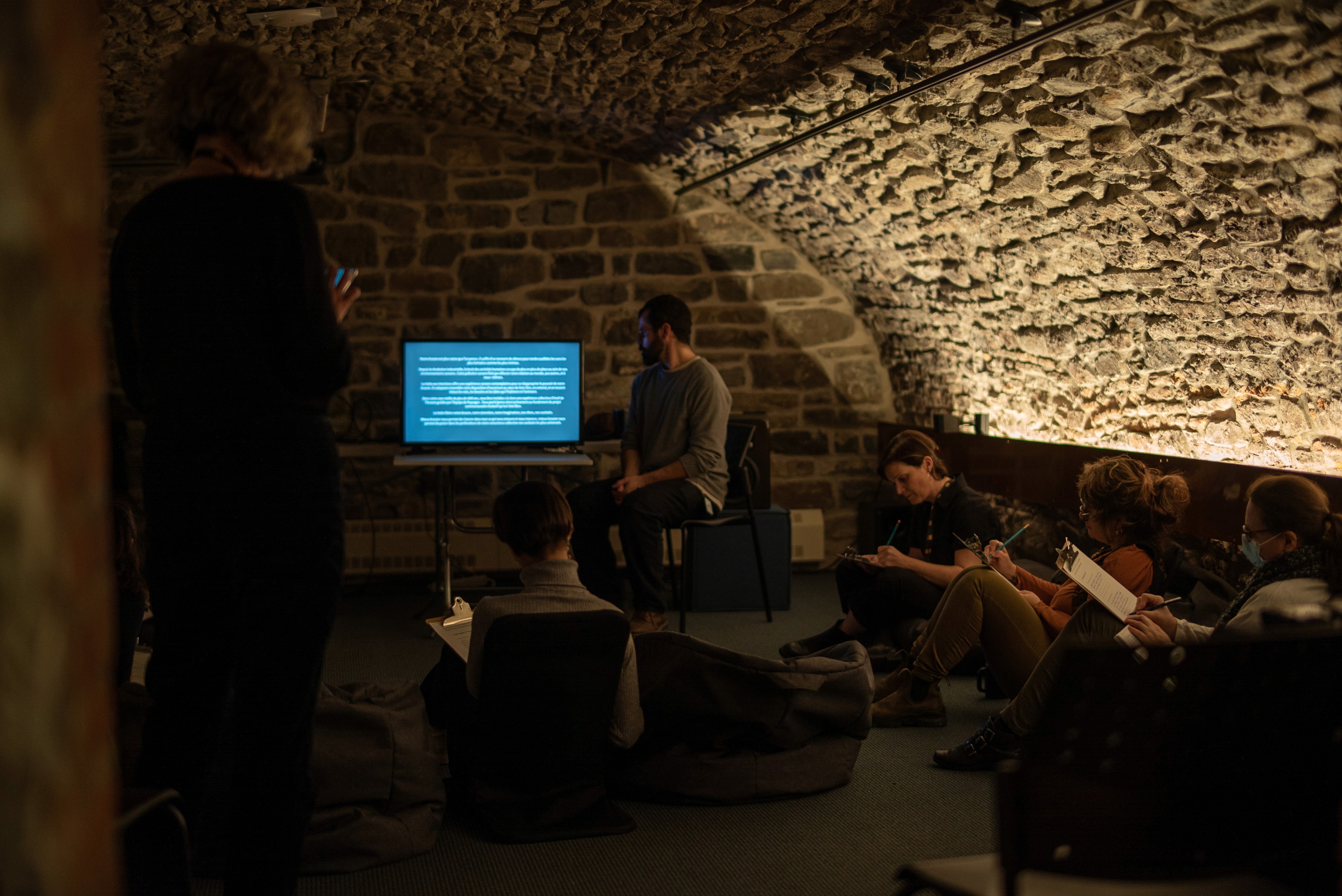 Gros plan sur un mur de pierre voûté équipé de petits haut-parleurs orientés vers une installation immersive.
