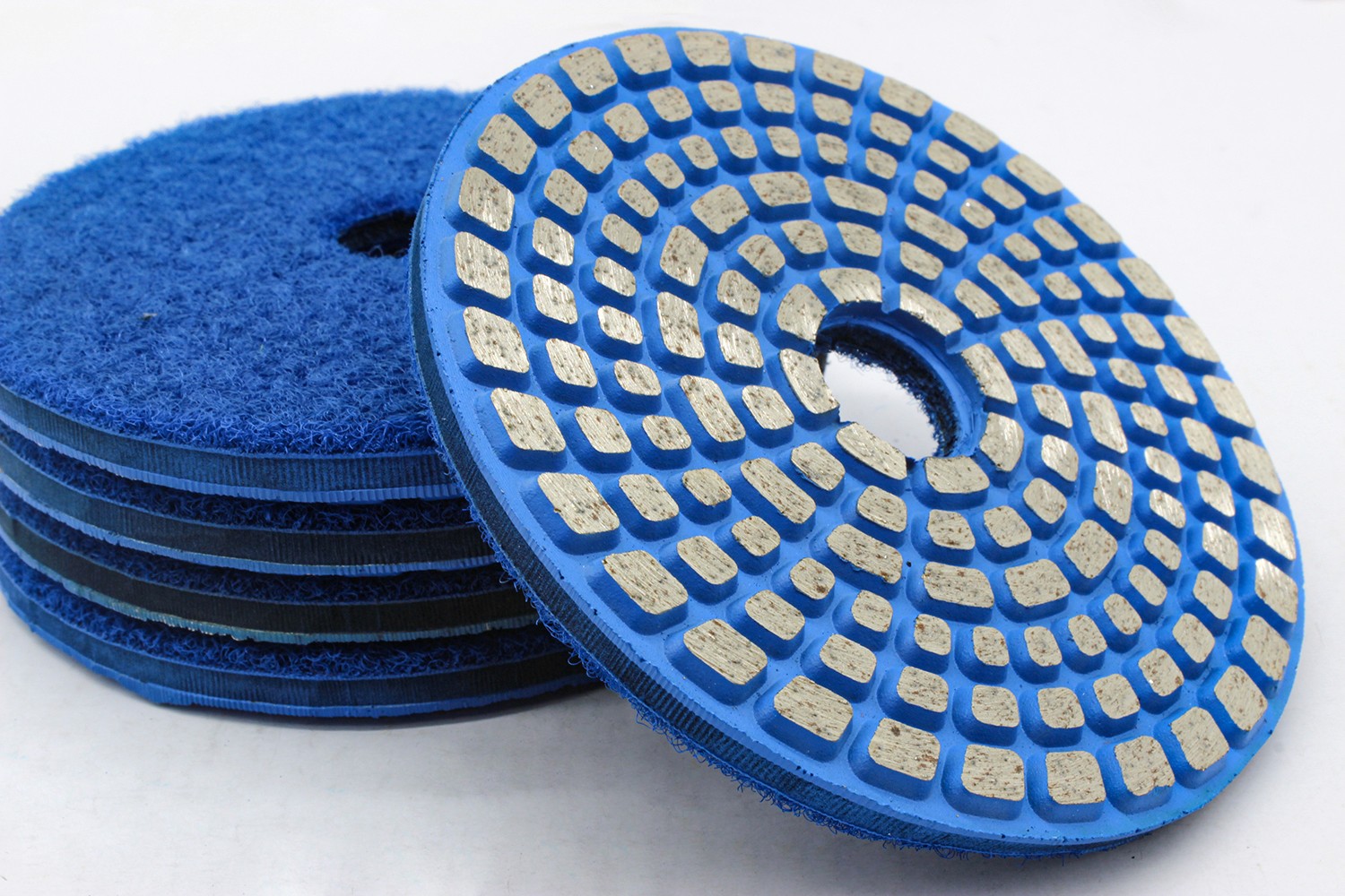 A close-up of blue resin bond diamond polishing pads stacked together, highlighting the detailed texture.