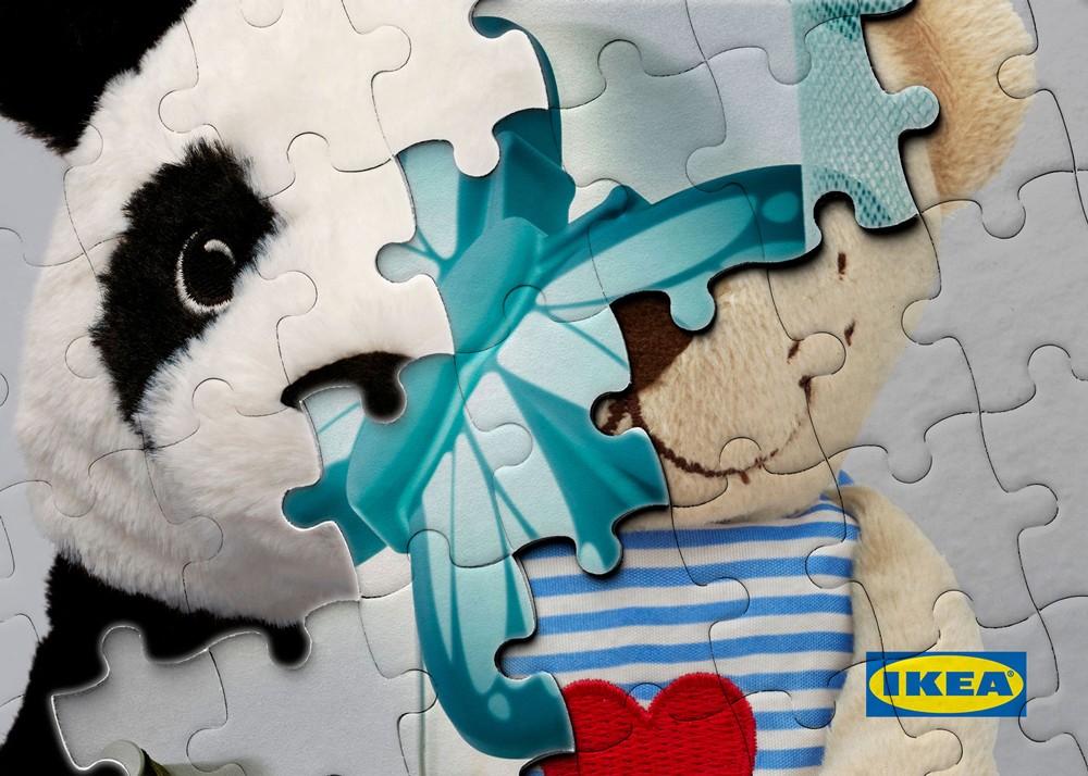 A panda soft toy and a striped bear soft toy positioned among jigsaw puzzle pieces on a light surface, part of the IKEA Junior Designers activity materials.