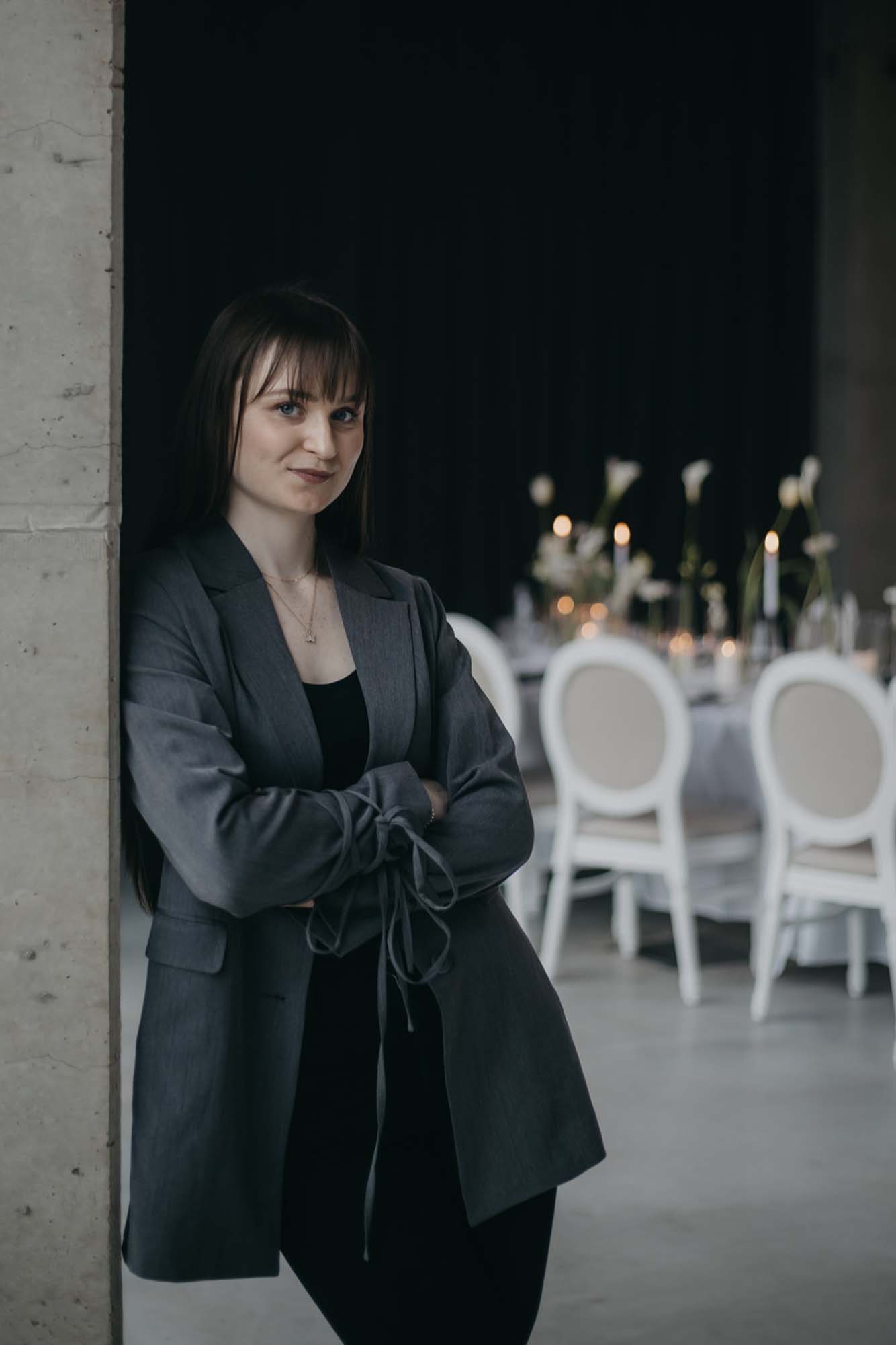 Hochzeitsplanerin Emily schaut lächelnd in die Kamera und im Hintergrund ist eine Tischdekoration einer Hohchzeit zu sehen.