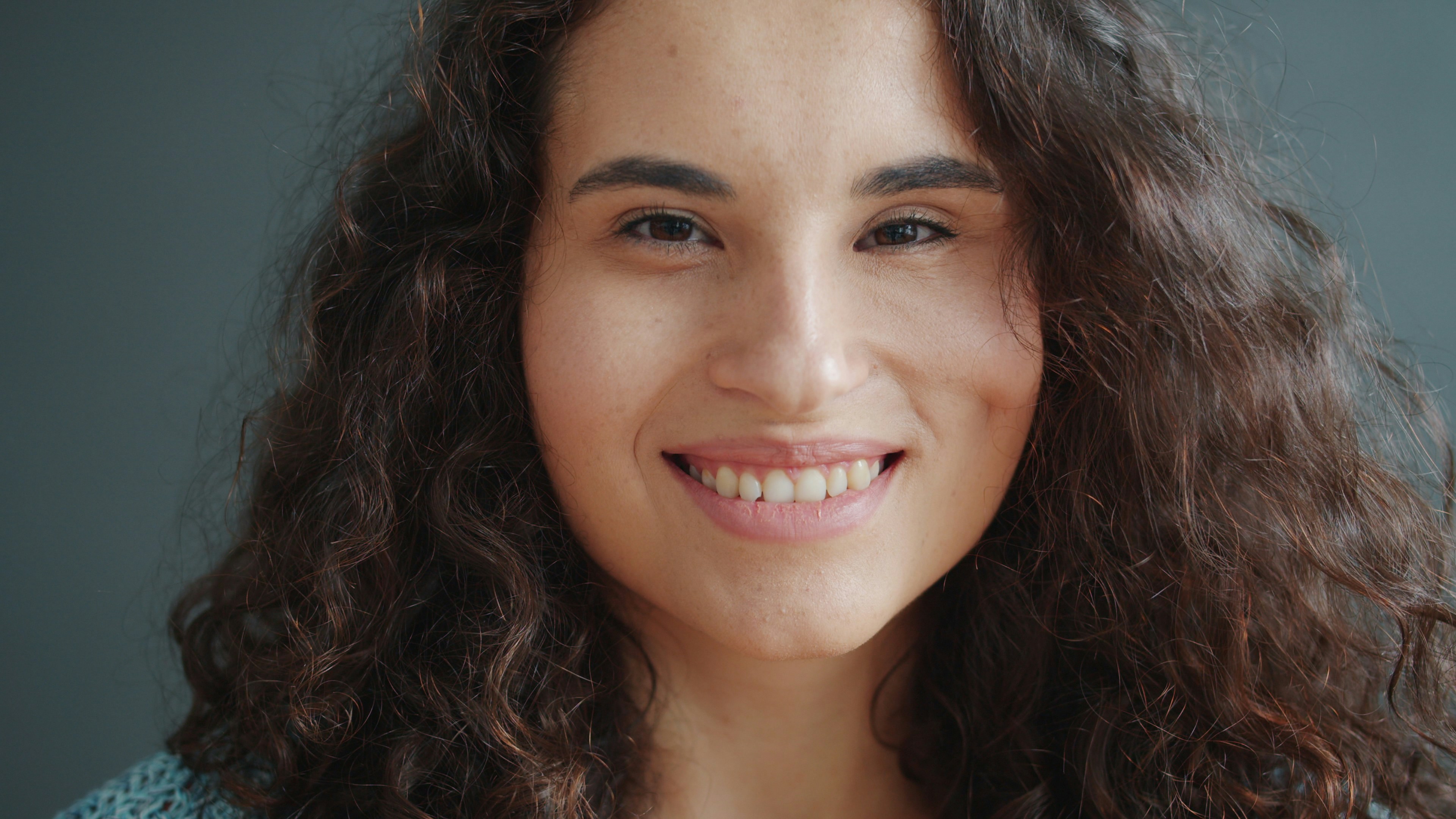 A young woman with curly hair smiles.