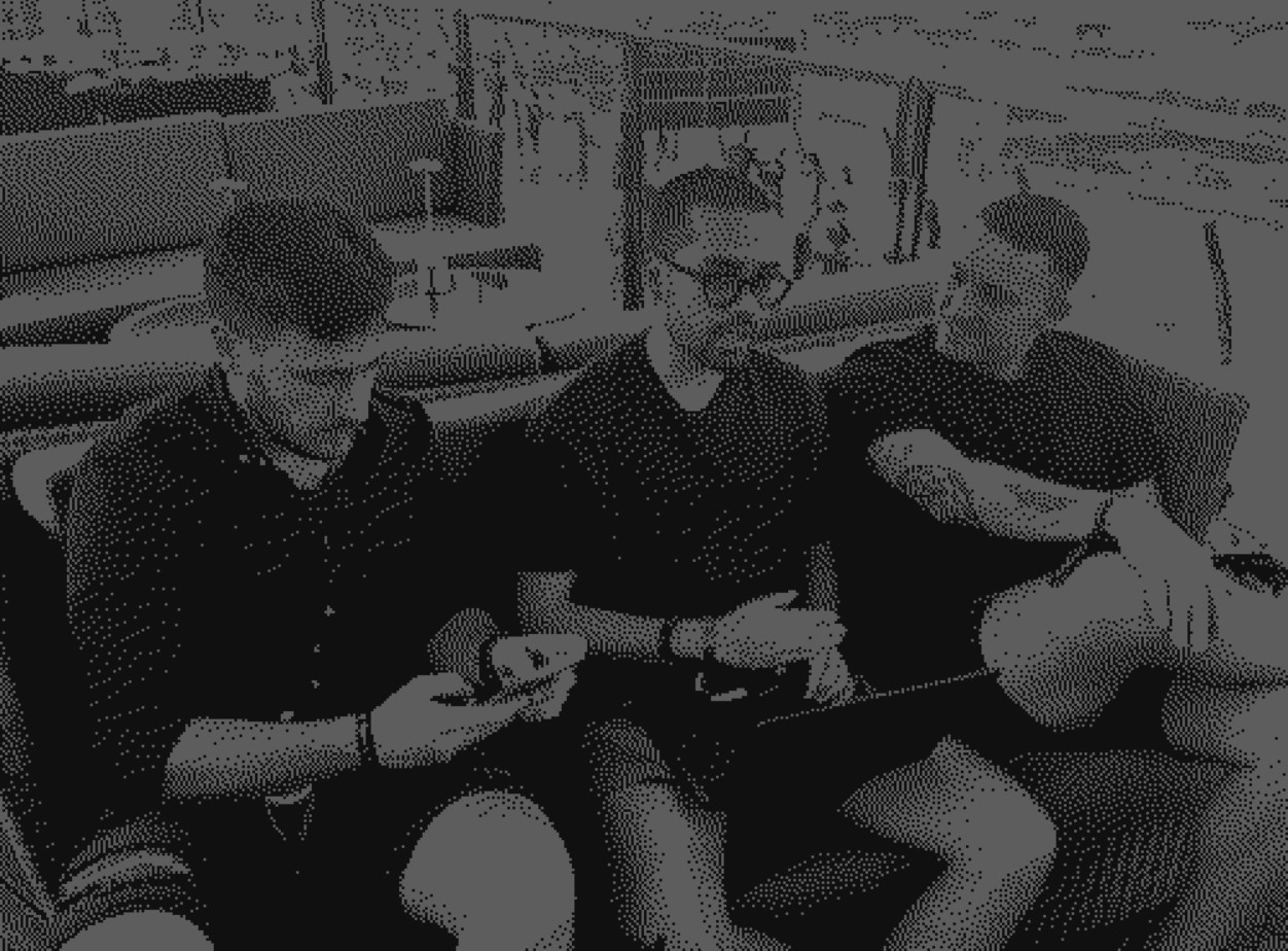 A large group photo of diverse team members gathered in an industrial-style space with arched ceiling.