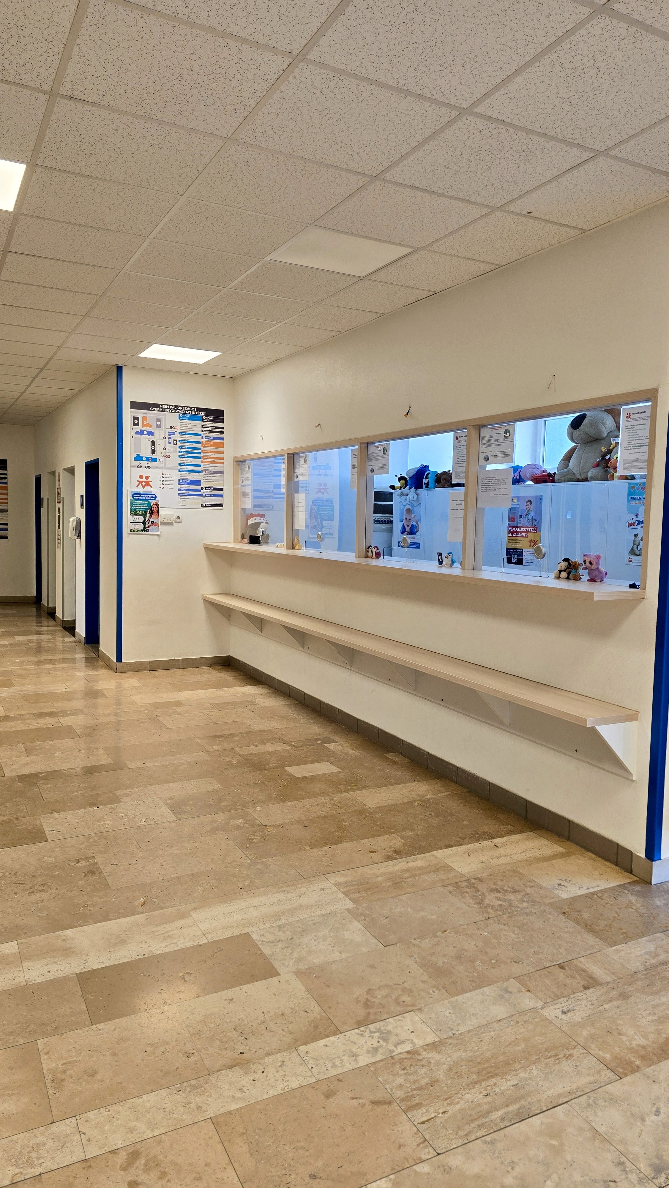 Felvételi iroda recepció üveges falfelület előtte táskatartóval.