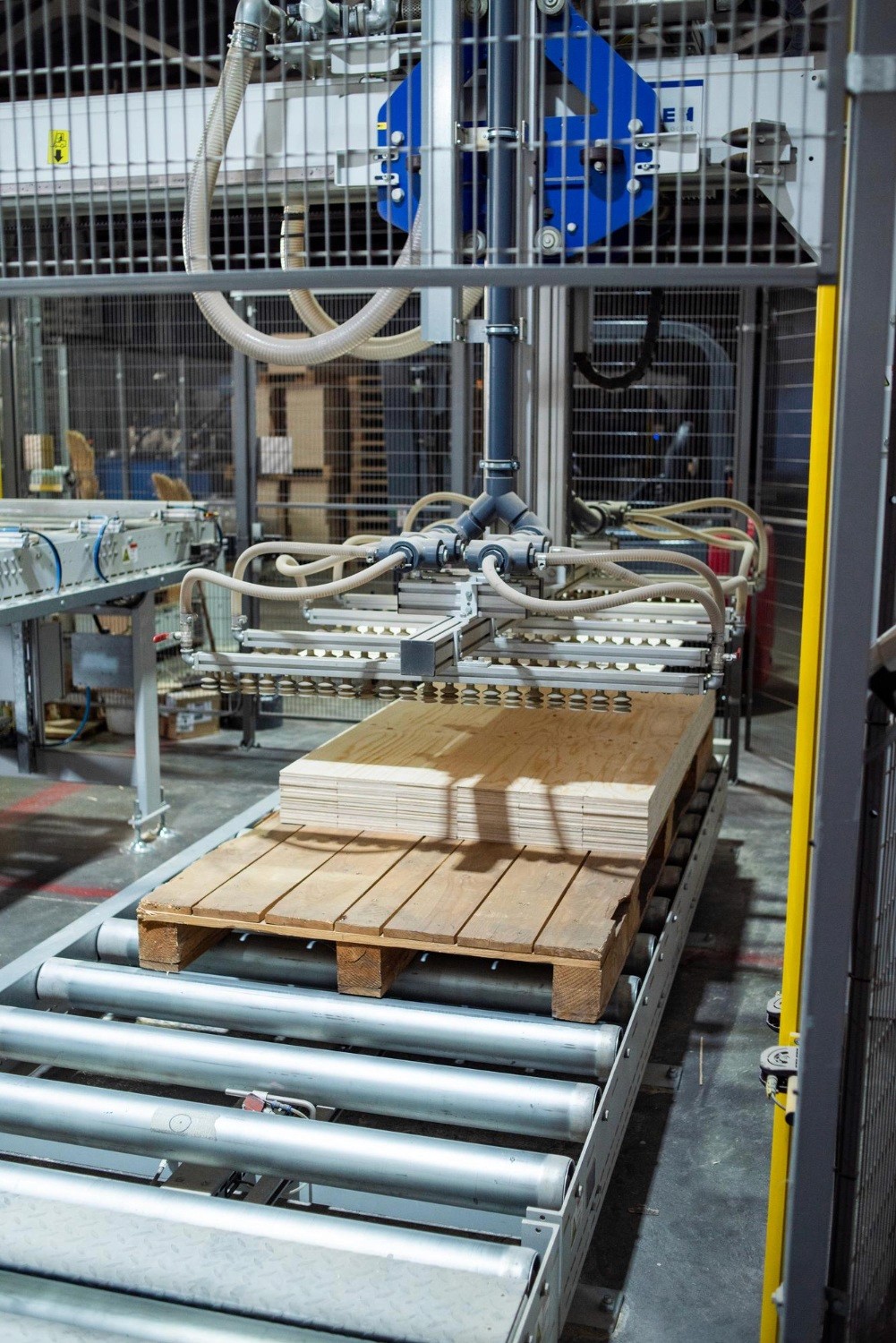 Robotic palletizing system handling stacked plywood on wooden pallets