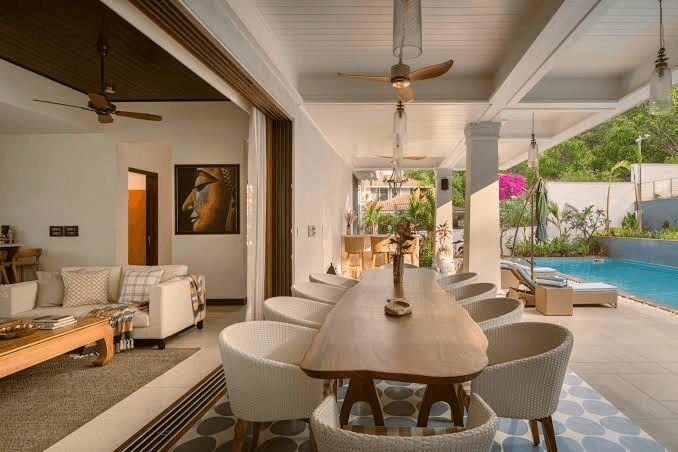 Coastal luxury home with stone and glass design perched on a cliff. Infinity pool, wooden deck, and ocean views evoke tranquility and sophistication.