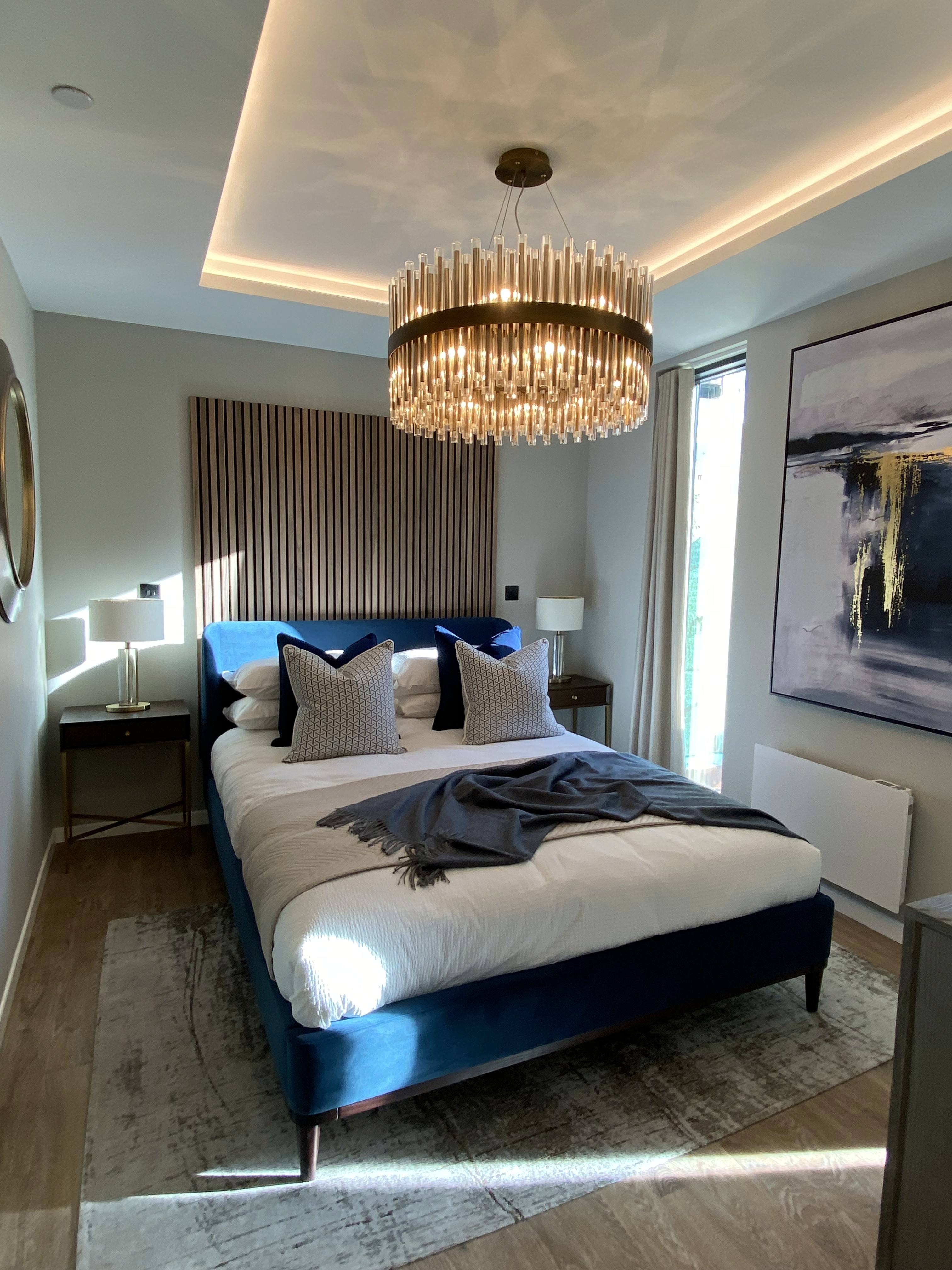 Master bedroom with large modern light fitting, timber accent wall, inset LED ceiling feature and modern, comfortable decor