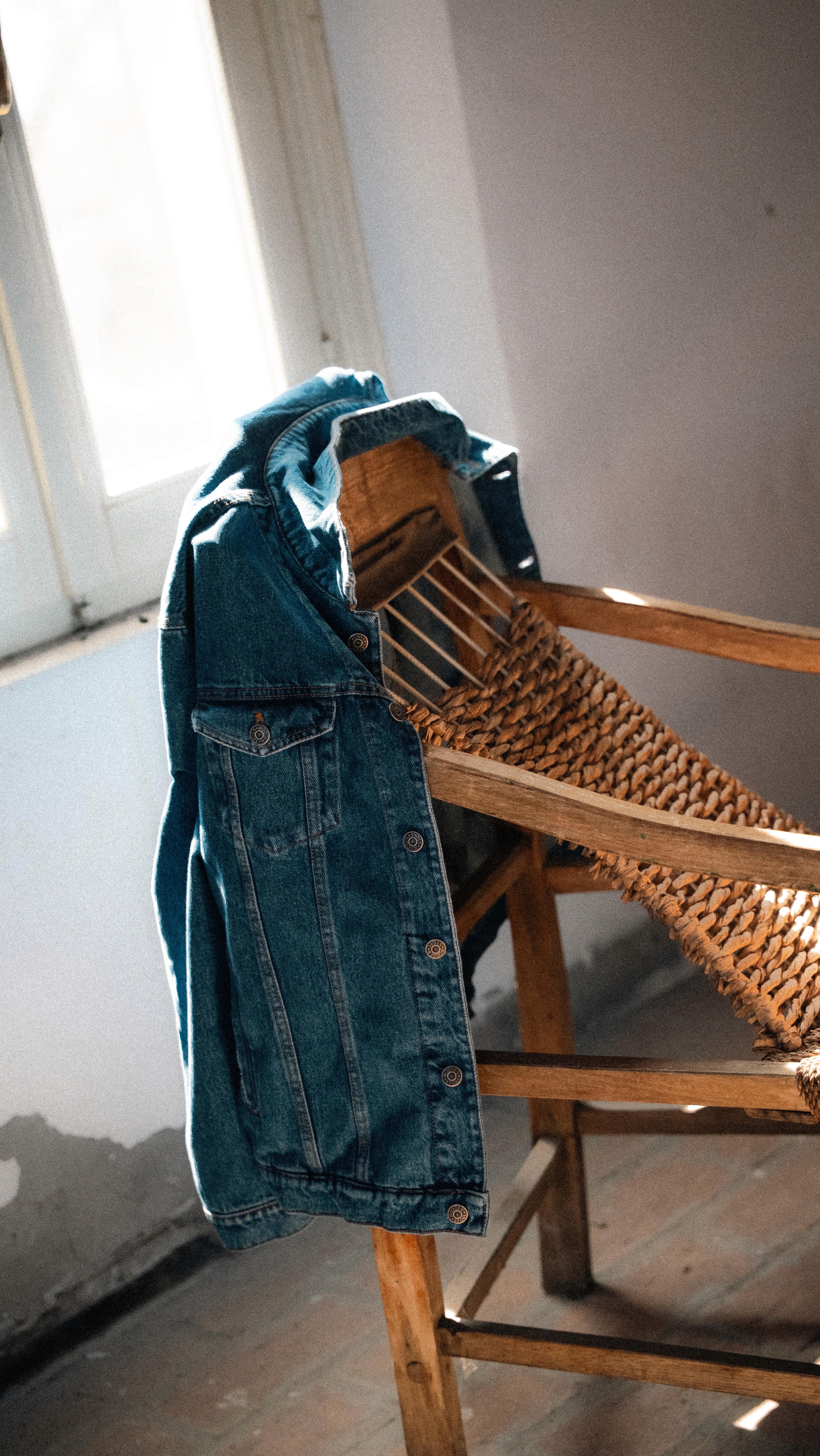 Nature morte d'une veste en denim posée sur une chaise dans le lookbook FW25 de Wooden Store