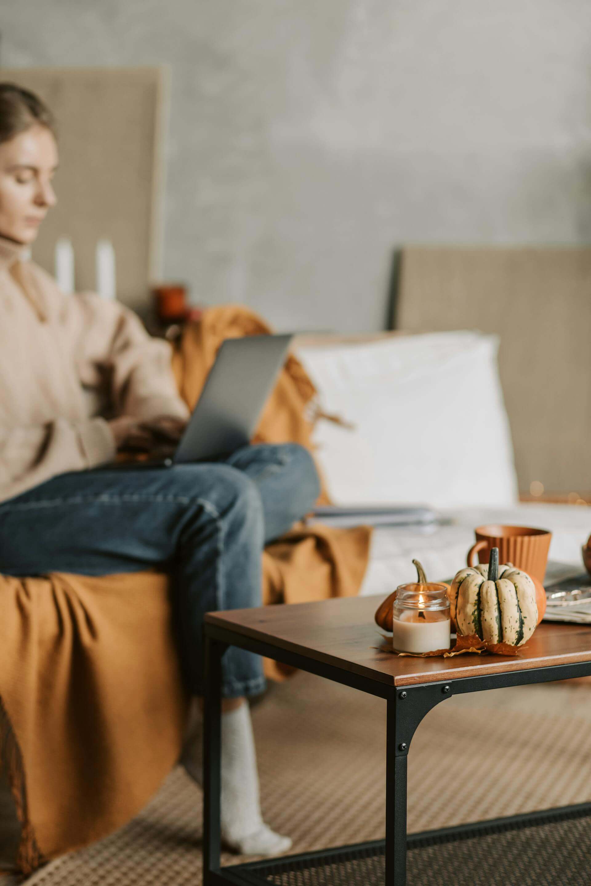 A woman seated on a couch, focused on her laptop, creating a cozy and productive atmosphere