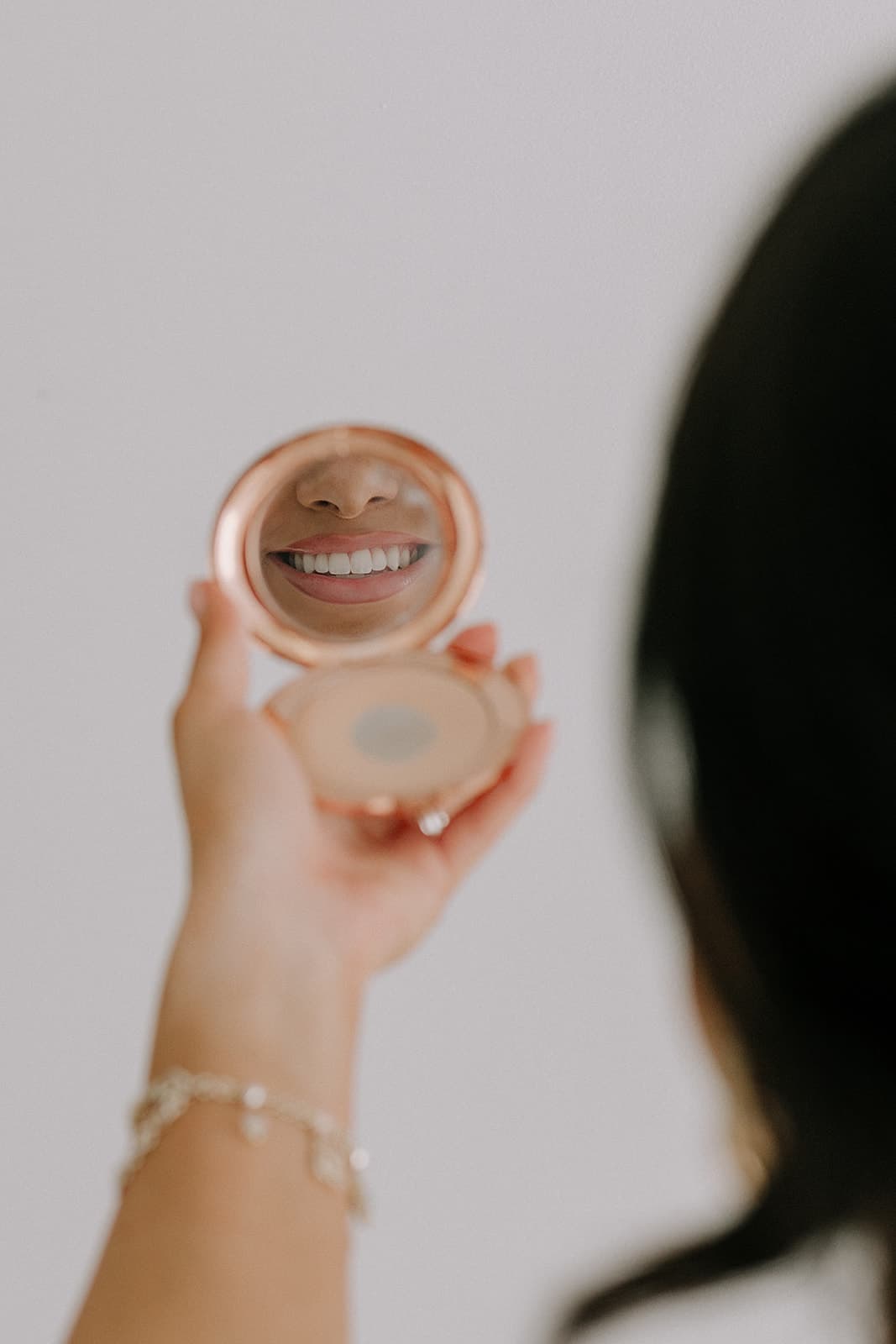 The reflection of a smile is seen in a compact mirror, captured beautifully in the natural light at Revelator Studio in Shreveport.