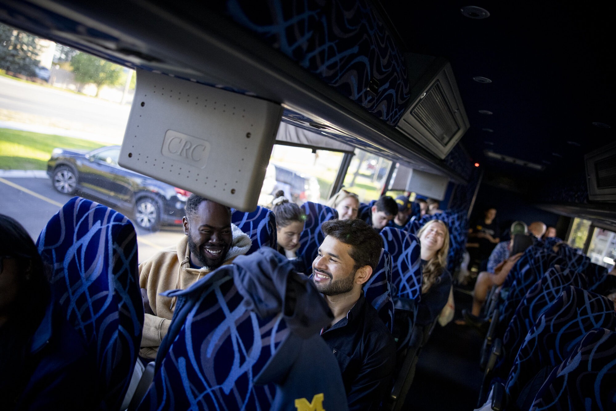 Interior of a bus with passengers seated, sunlight streaming through the windows.