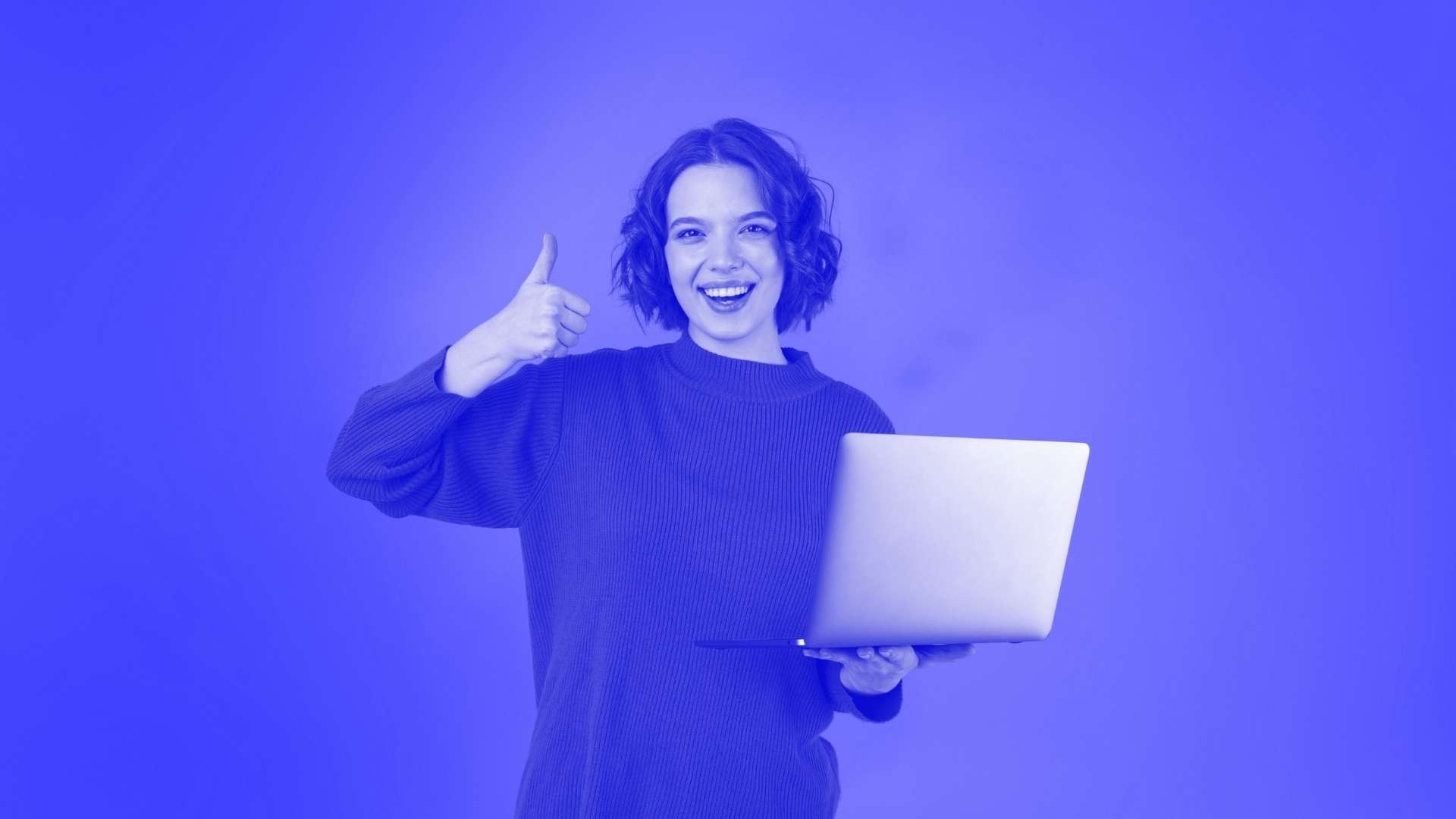 A smiling lady holding a laptop and putting a thumb up