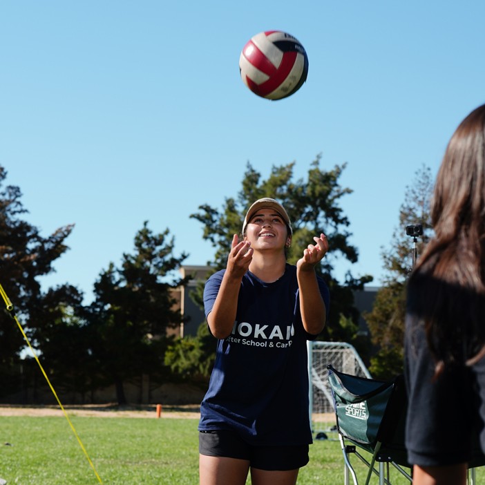 Educator guiding students through a skill-building volleyball drill in a school gym setting
