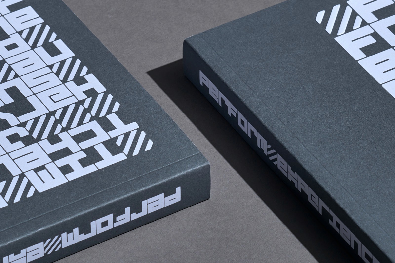 Two black books with abstract white designs on the covers, positioned at an angle against a gray background.