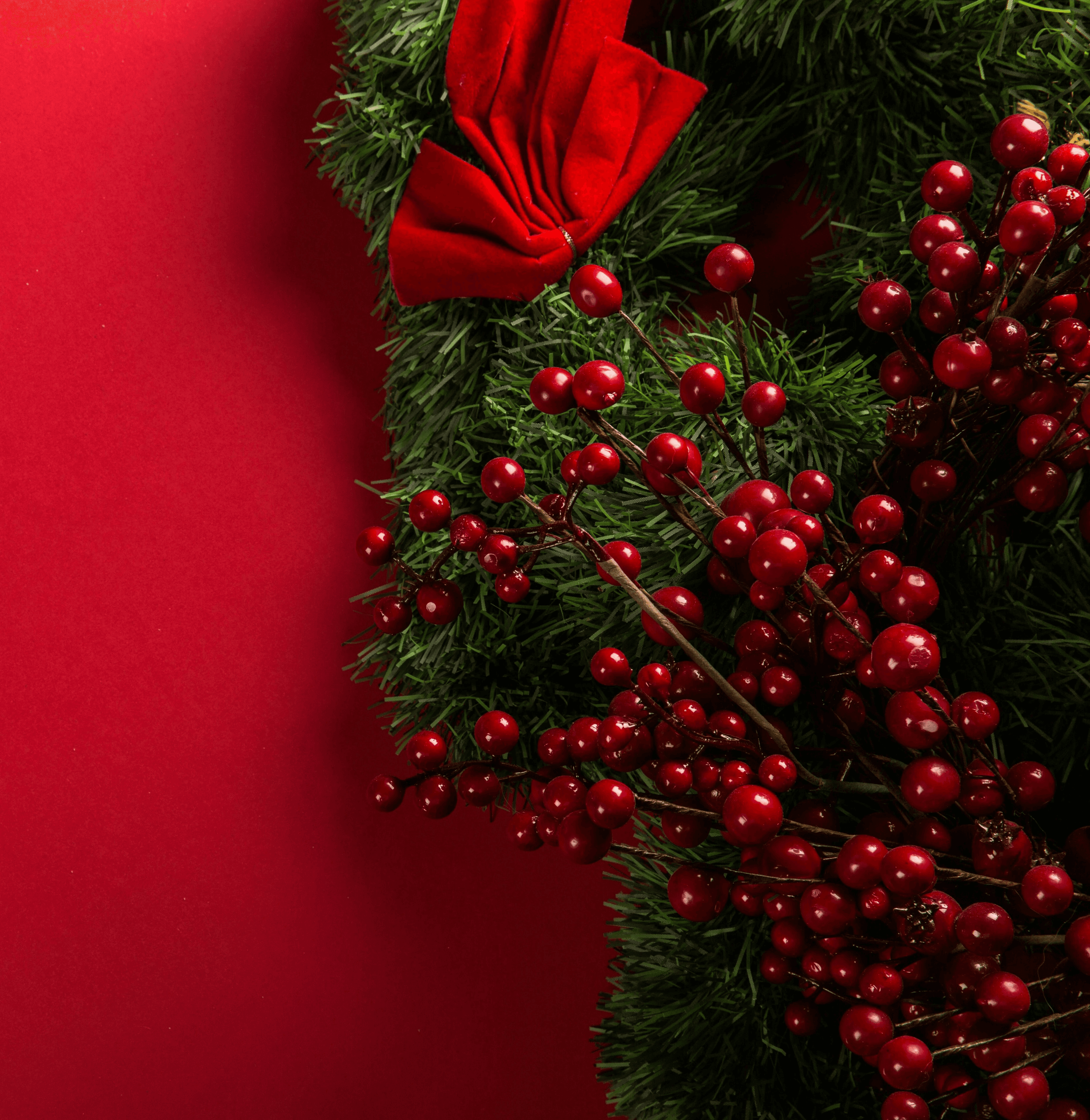 a close up of a christmas wreath on a red background