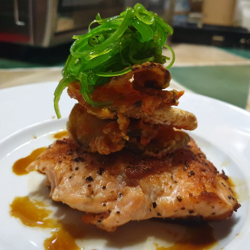 Grilled Sesame Salmon topped with tempura onion rings and seaweed salad.