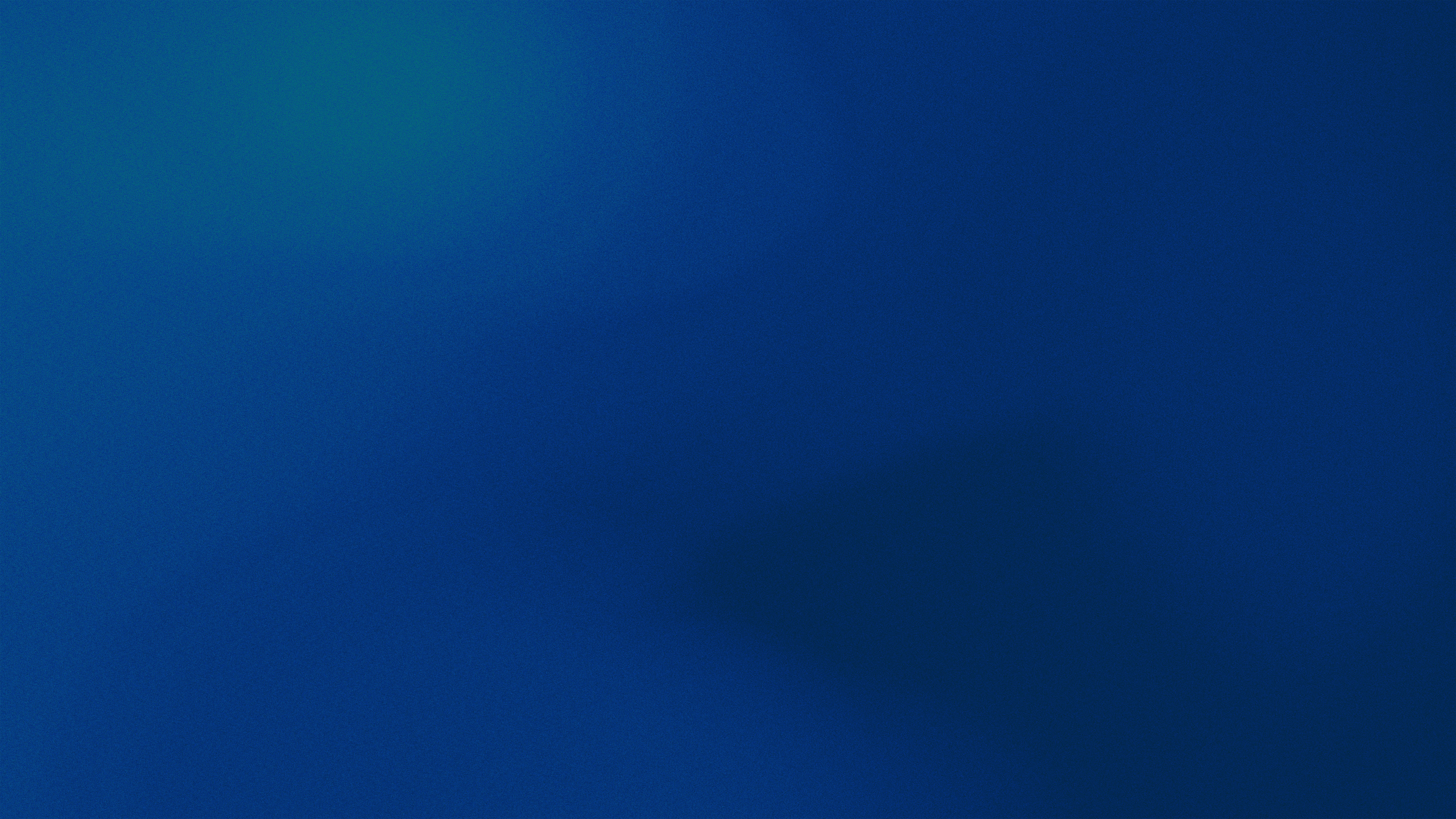 A man stands while two people sit at a table in an office setting, smiling and engaged in conversation. The mood is friendly and collaborative.