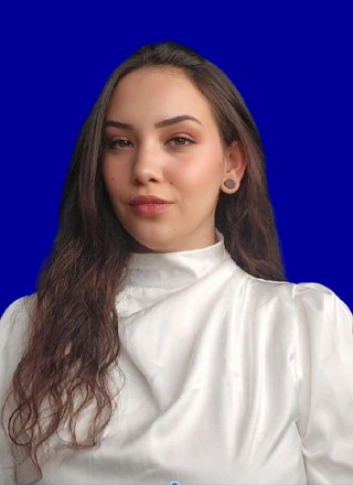 A smiling young man with crossed arms, wearing a plaid shirt and white t-shirt, poses against a dark background.
