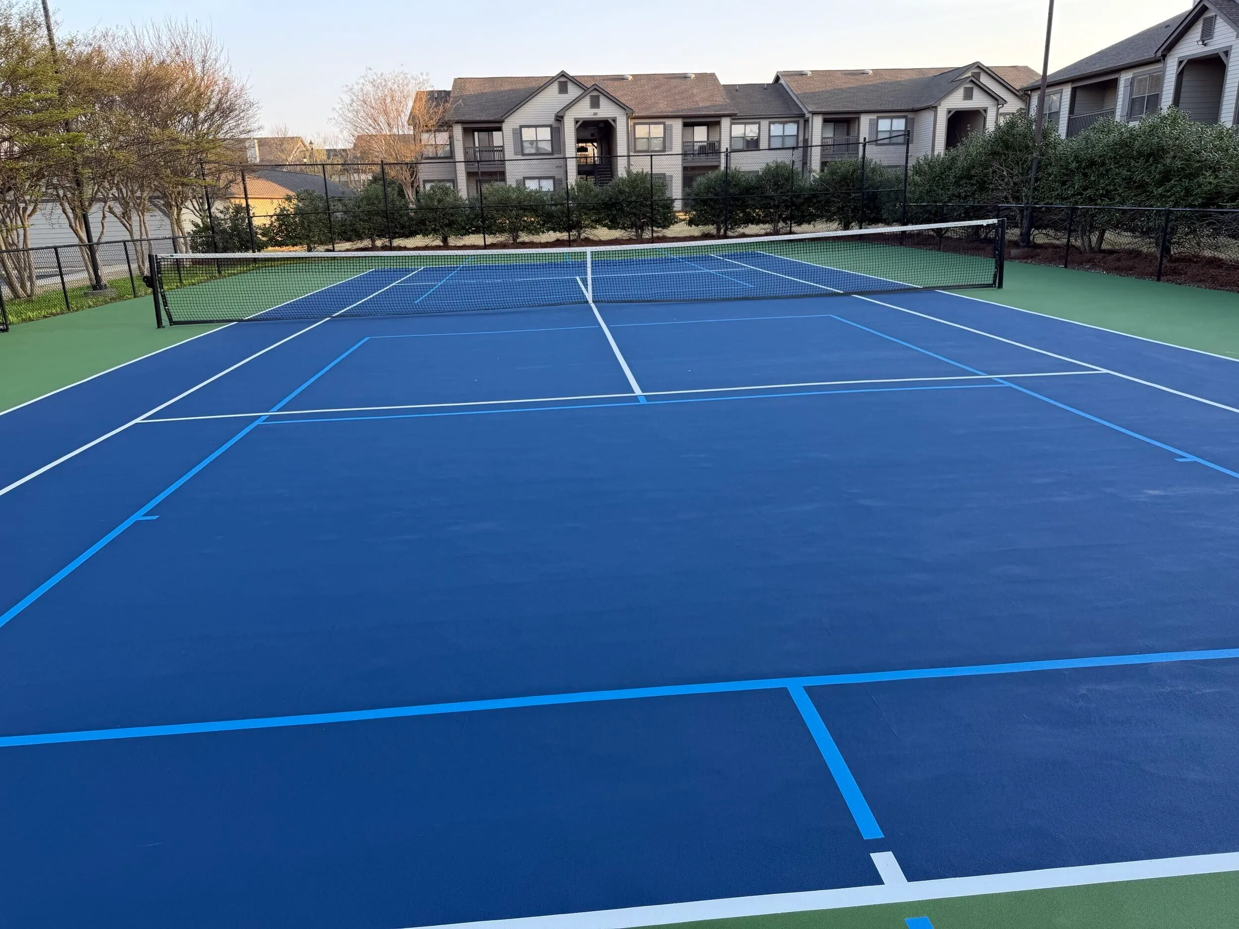 Resurfaced apartment tennis court with blue coating and white striping at Weston Ranch in Madison, AL