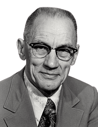 Black and white portrait of an elderly man with short, neatly combed hair, wearing glasses and a light-colored suit. He has a gentle smile and a warm, approachable expression, with slight wrinkles indicating his age. His patterned tie and formal attire convey professionalism and dignity.