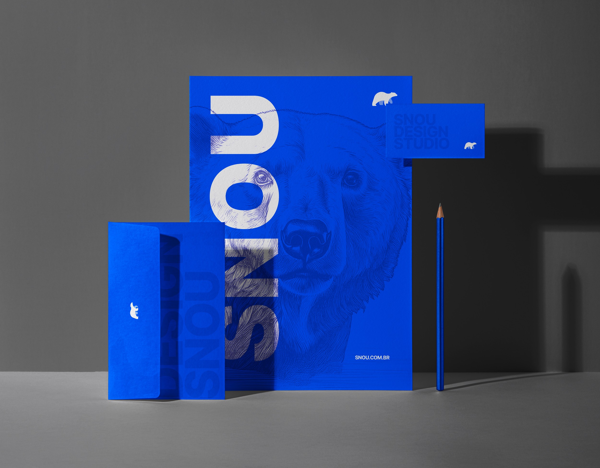 Imagem da identidade visual do estúdio Snou Design. Um envelope, um papel carta, um cartão de visitas e um lápis na cor azul. Como arte a imagem de um urso polar símbolo da empresa está desenhado com traços de lápis.