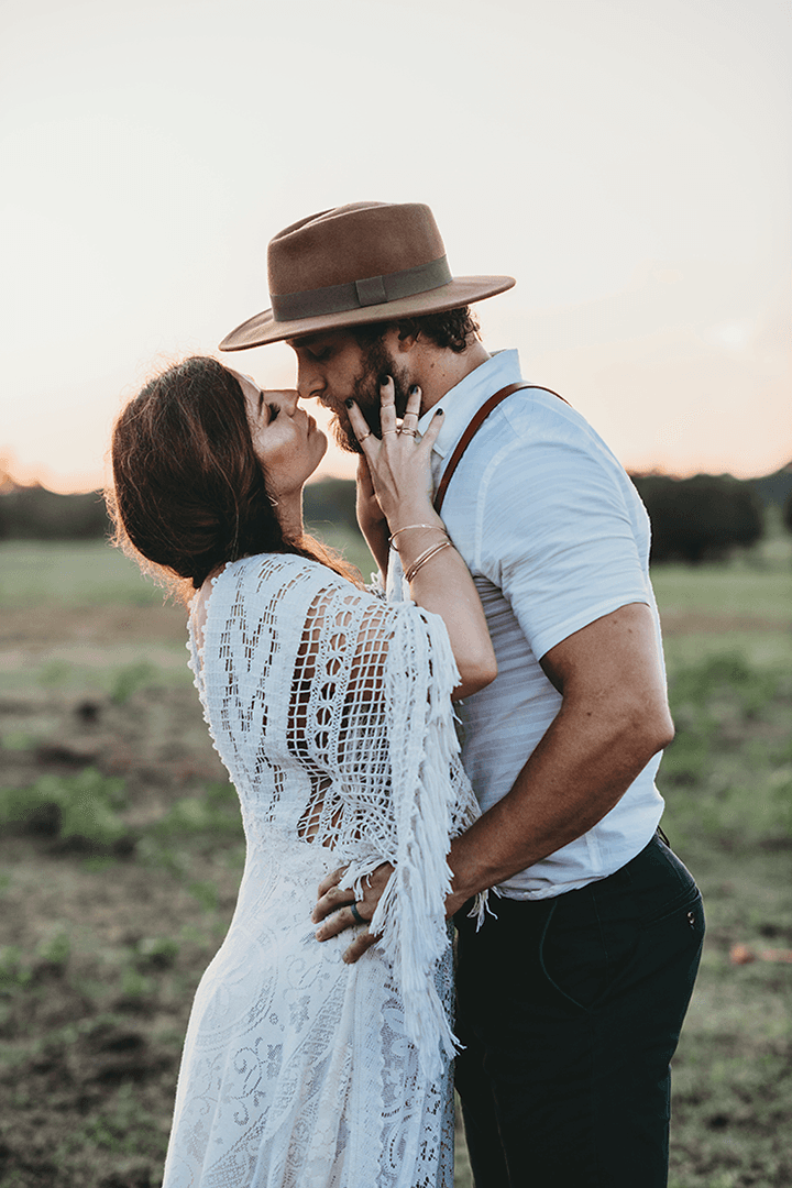 A couple stands outdoors at sunset.