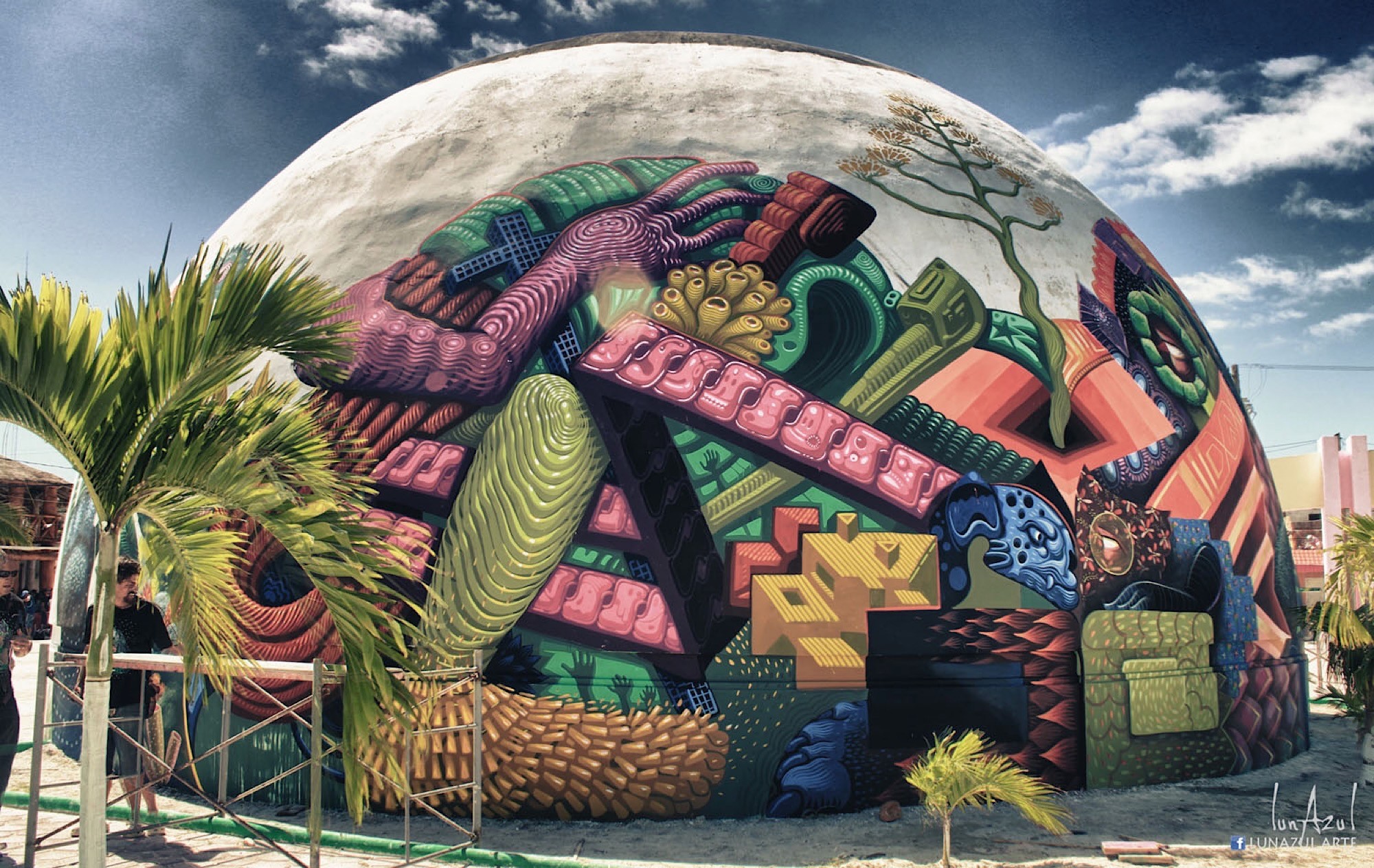 The finished dome glows with tumbling geometric forms in pink, green and orange beneath palms.