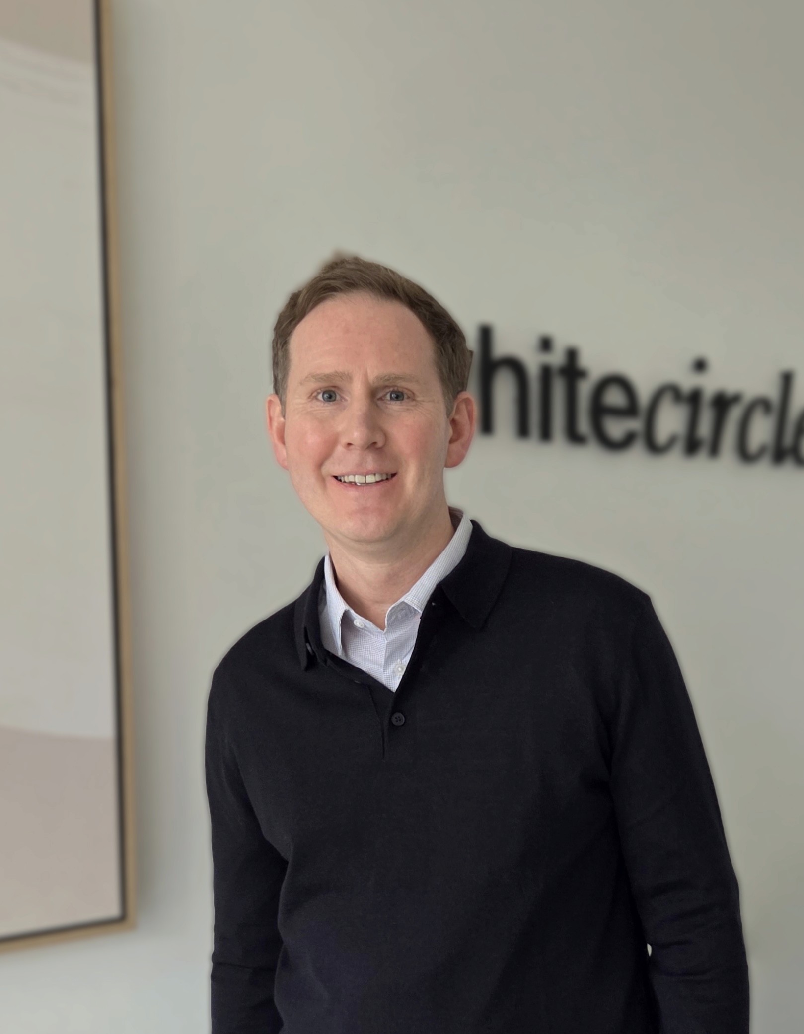 a man in a blue shirt smiling at the camera