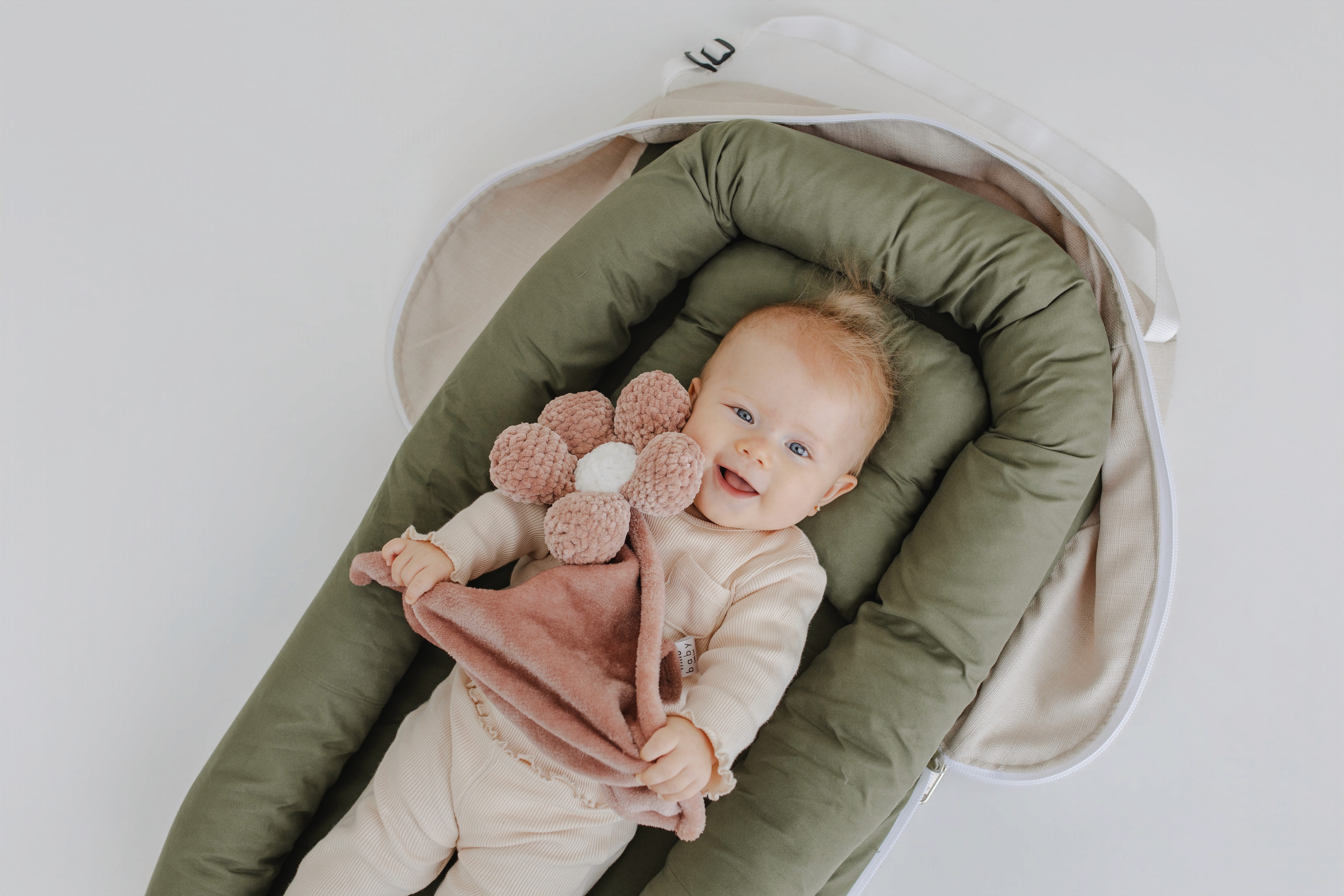 A couple in wedding attire walks hand in hand across a sunlit field.