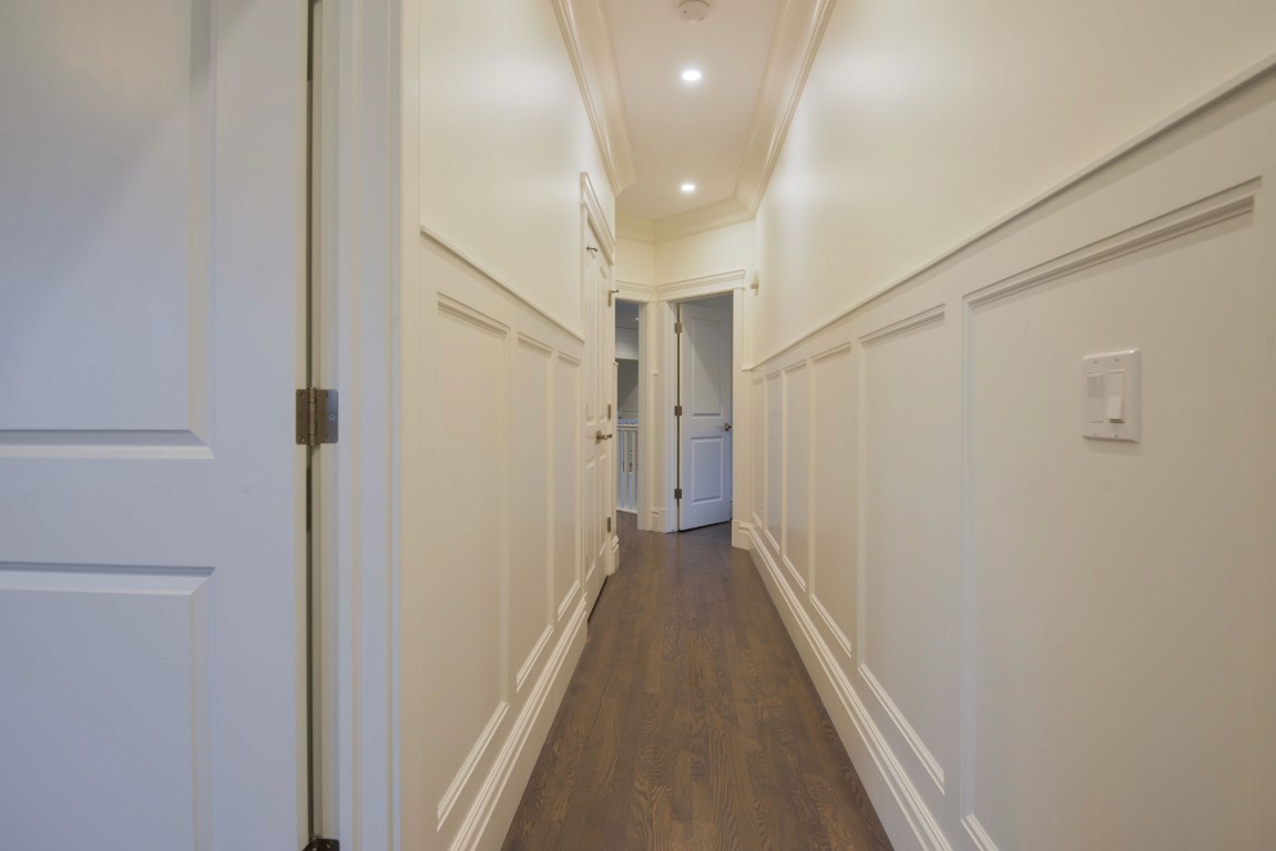 Image of KHD Homes design-build interior with wainscoting, recessed lighting, and wood floors leading to primary suites.