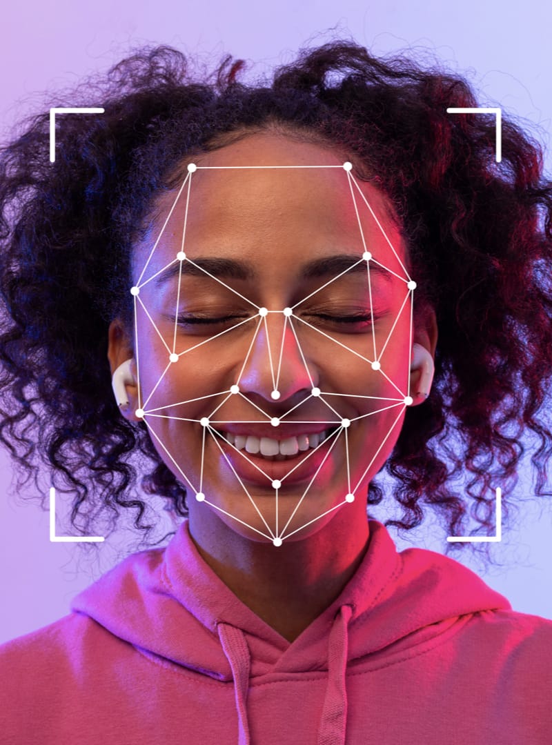 A close-up photo of  young woman with lines and dots representing key parts of her face suggesting facial recognition technology