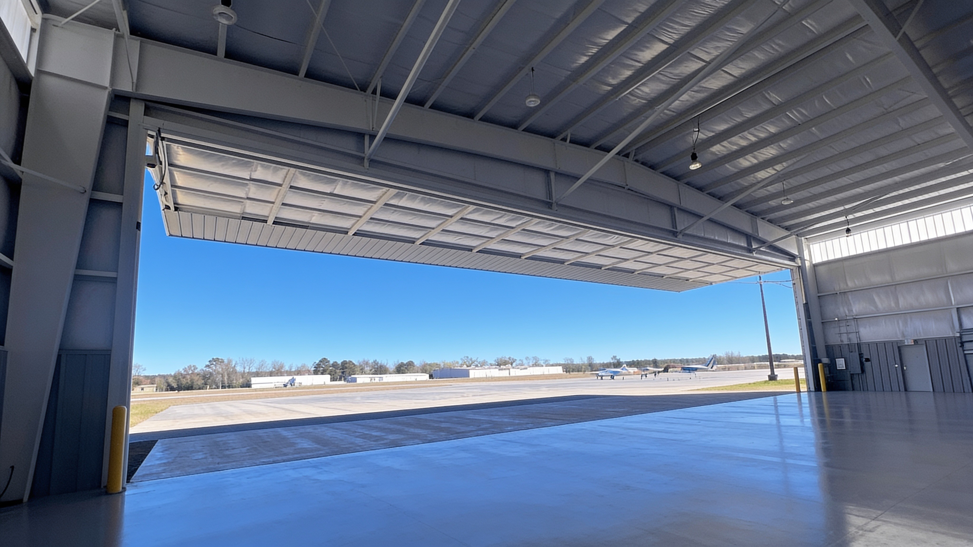 Aircraft hangar door forming a canopy over the apron