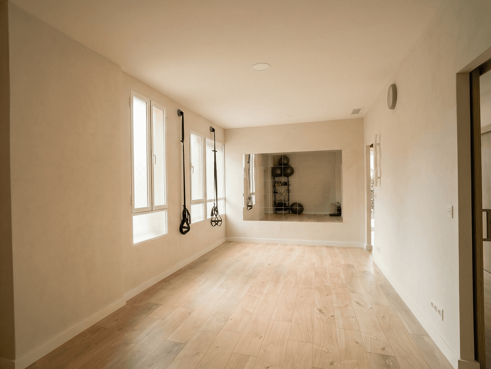 A serene and elegant spa space with wooden reclining chairs and white cushions. Golden sunlight filters through a cascading water feature, creating a peaceful atmosphere. Tropical plants and candles add to the relaxing ambiance.