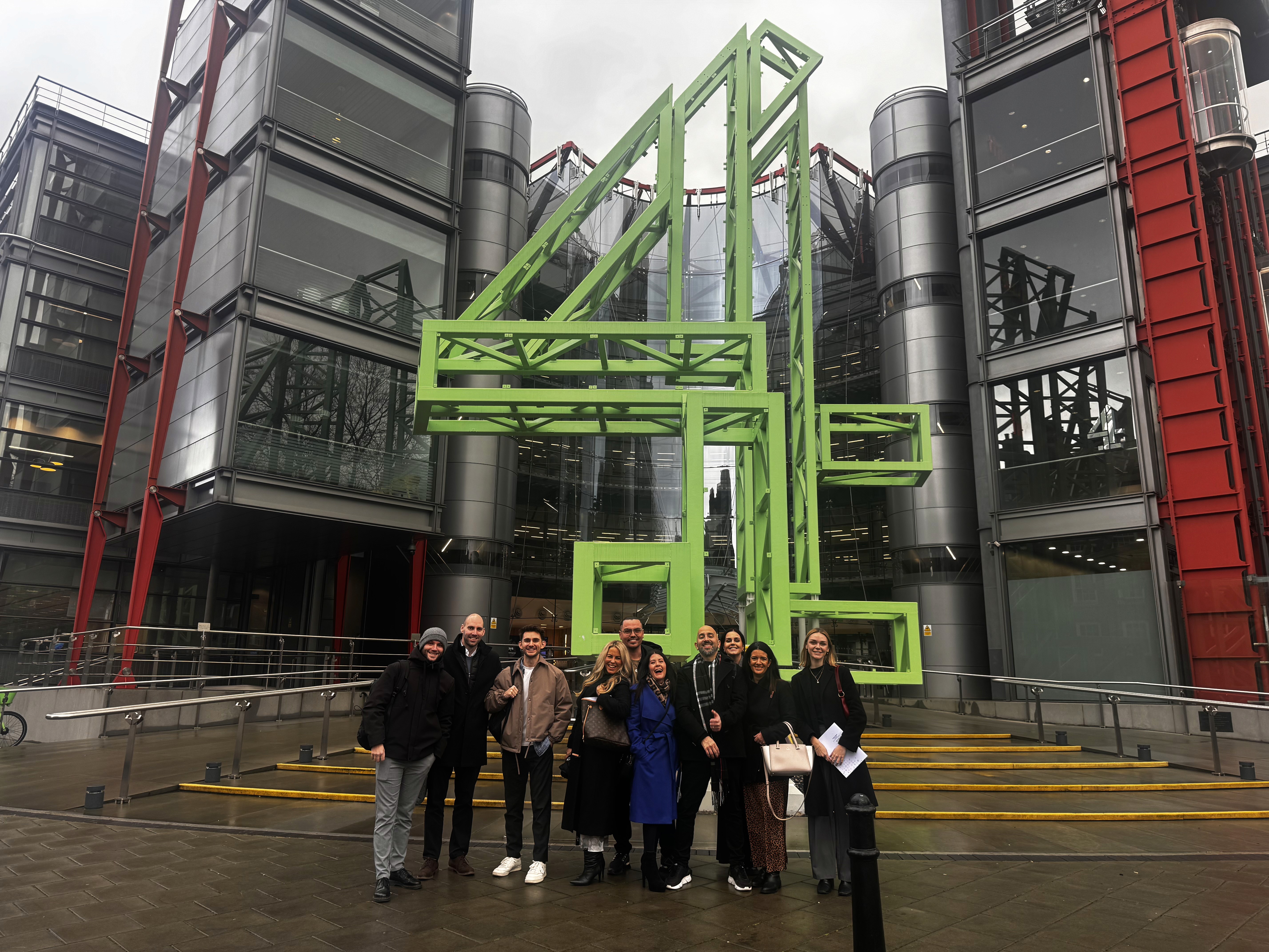 People seated at a table with laptops and water bottles, engaged in discussion in a bright meeting room.