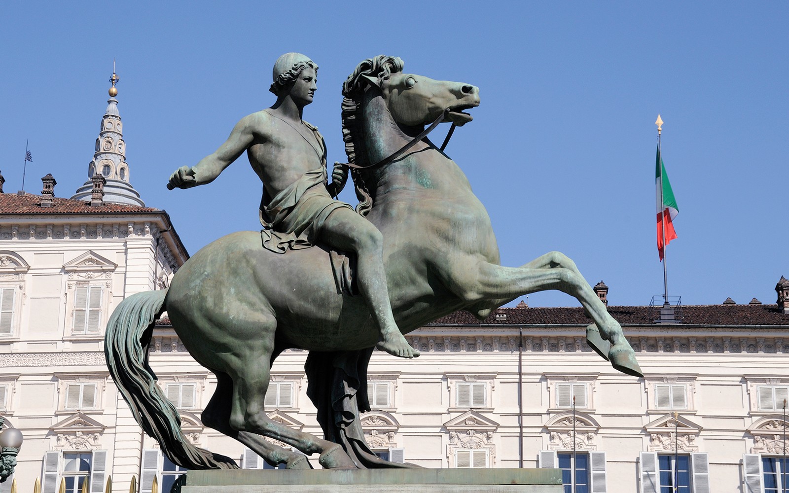 Rytterstatue foran Det kongelige slottsmuseum i Torino, med det italienske flagget.