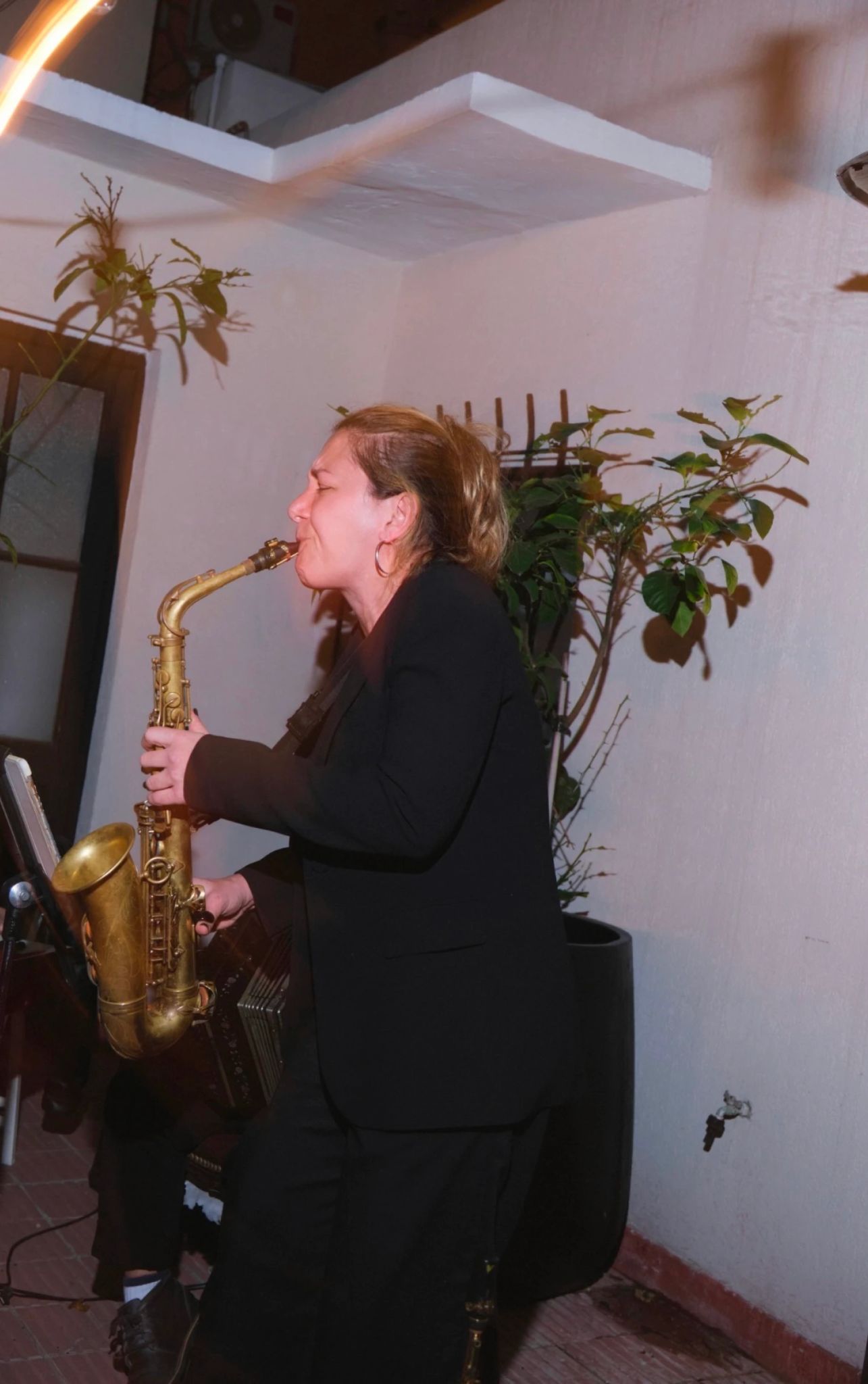 Mujer tocando un saxofón durante una presentación musical en vivo.