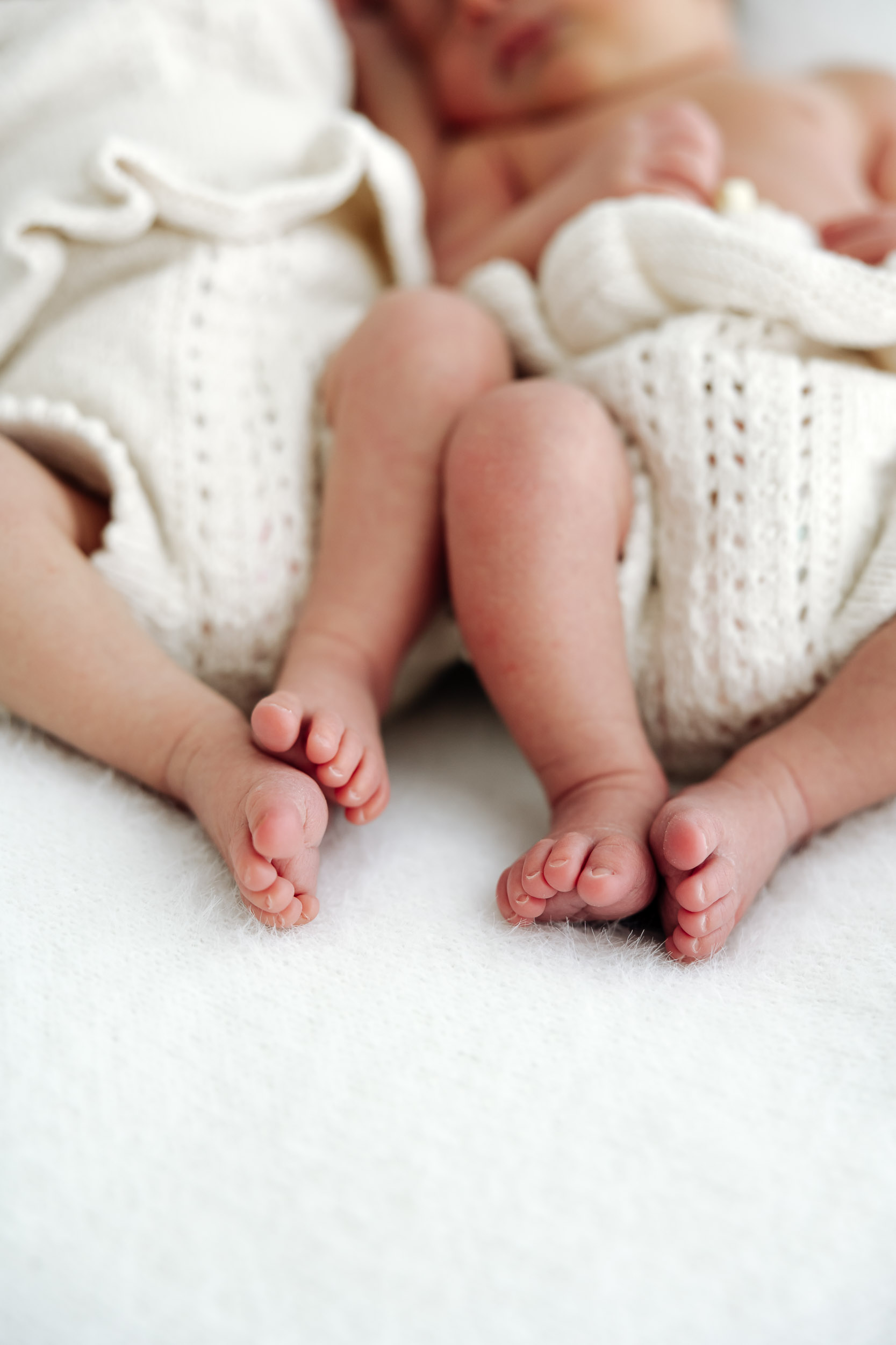 Mackay newborn photographer capturing twin babies feet in studio, peaceful sleeping twins photographed in neutral knits.