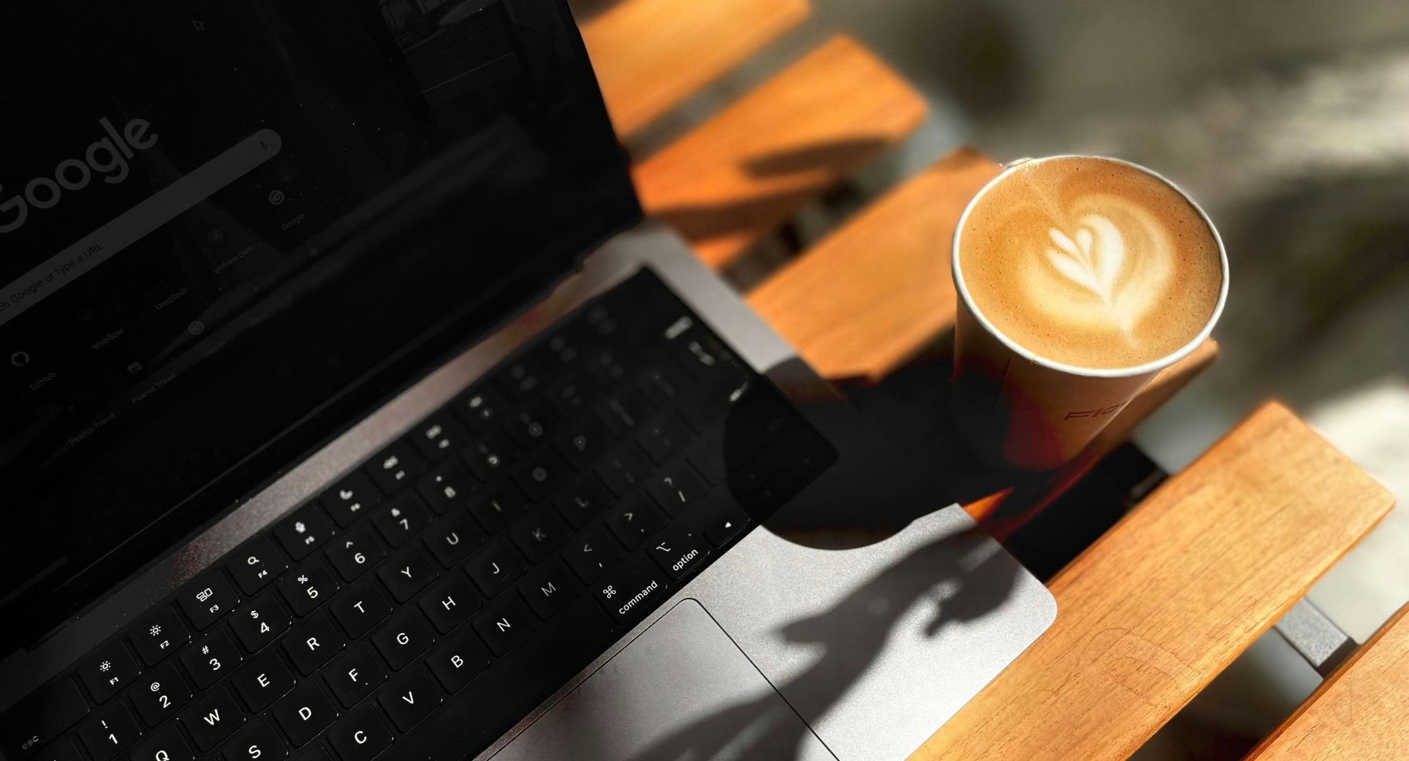 um notebook cinza com um café gourmet ao lado