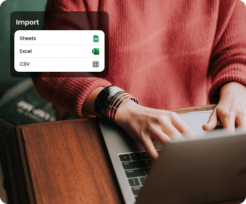 A woman wearing a purple sweater holds a green smartphone and smiles warmly under a clear blue sky, conveying happiness and connectivity.