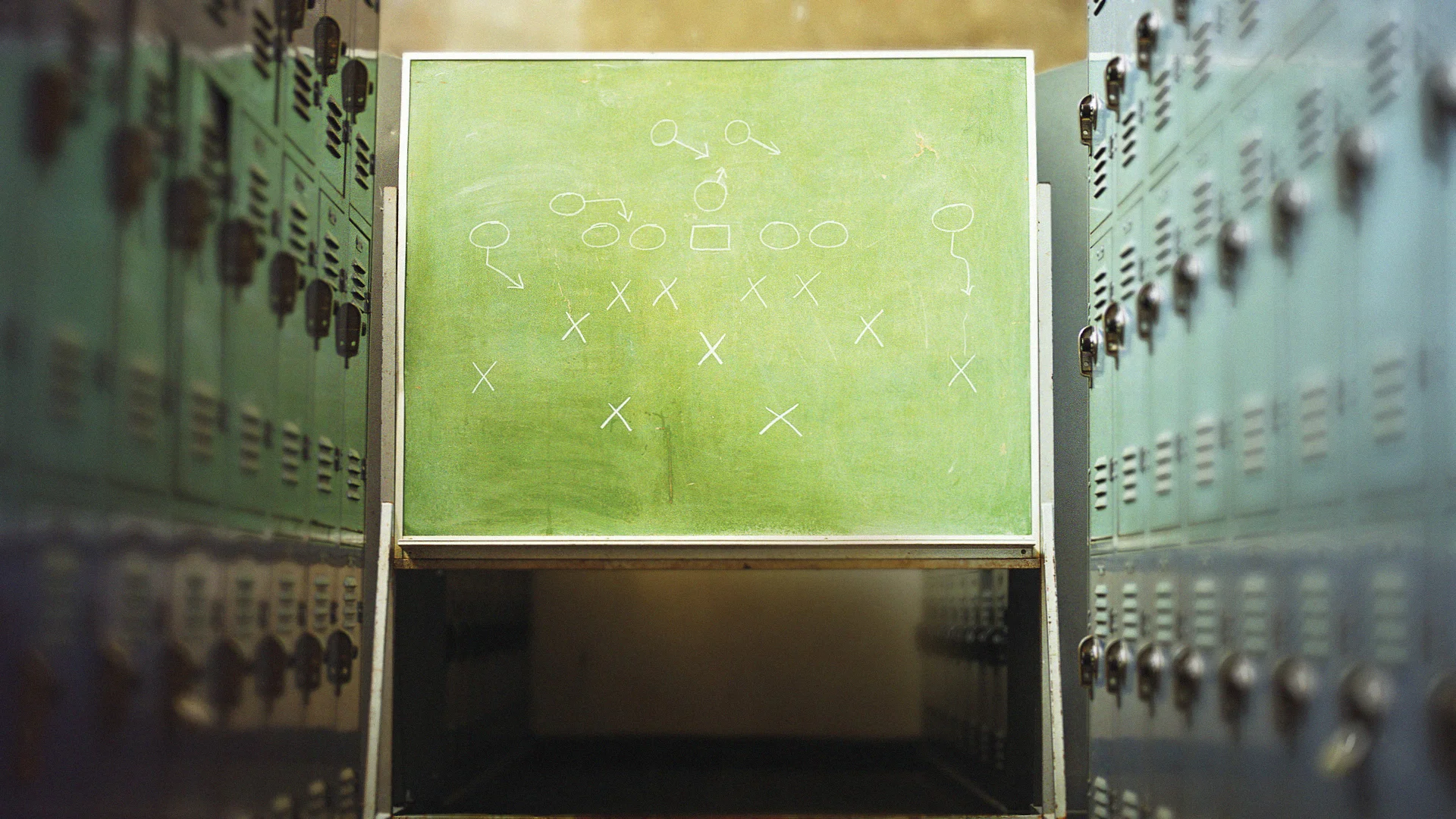 A locker room chalkboard with strategic plays drawn in white chalk
