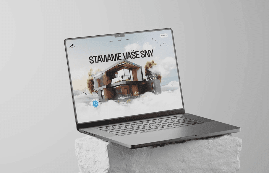 Modern laptop placed on a textured stone surface, displaying a website with the text ‘STAVIAME VAŠE SNY’ and an architectural visualization of a contemporary house floating in the clouds, symbolizing innovative home construction.