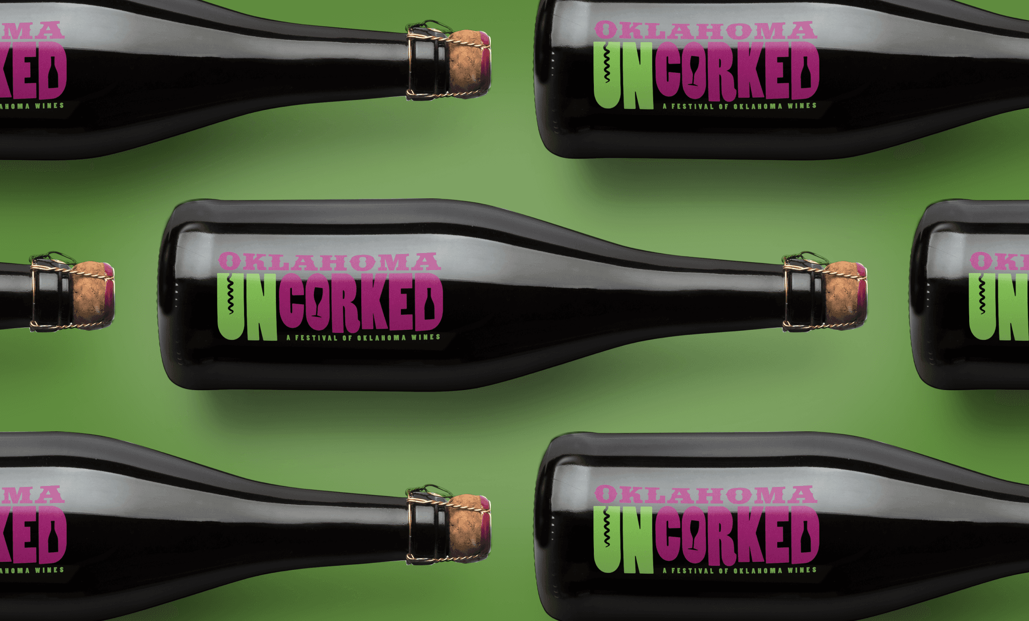 A dark wine bottle laying on it's side displaying a pink and green logo